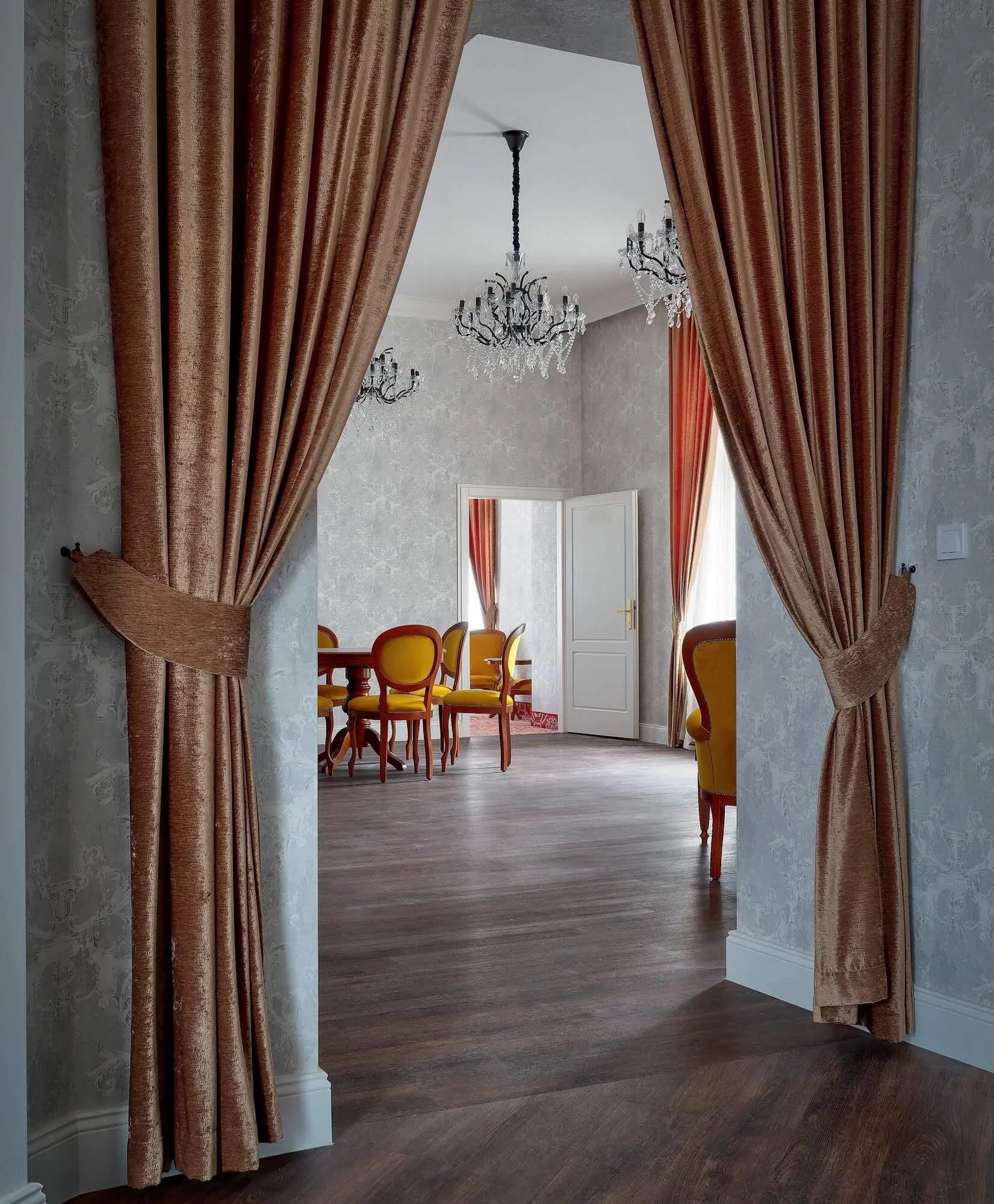 Elegant dining room with ornate curtains, chandelier, and yellow chairs.
