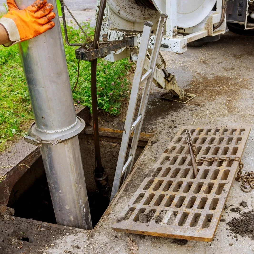 Technician servicing a sewage ejector pump system through an access chamber, diagnosing failures, blockages, and wastewater drainage issues.