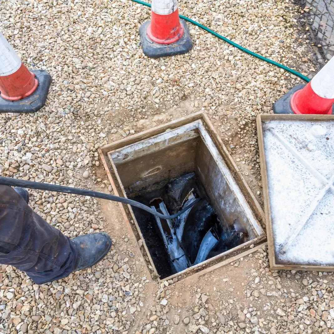 Technician inspecting a septic drain field access chamber during rejuvenation work, improving wastewater flow, soil absorption, and system performance.