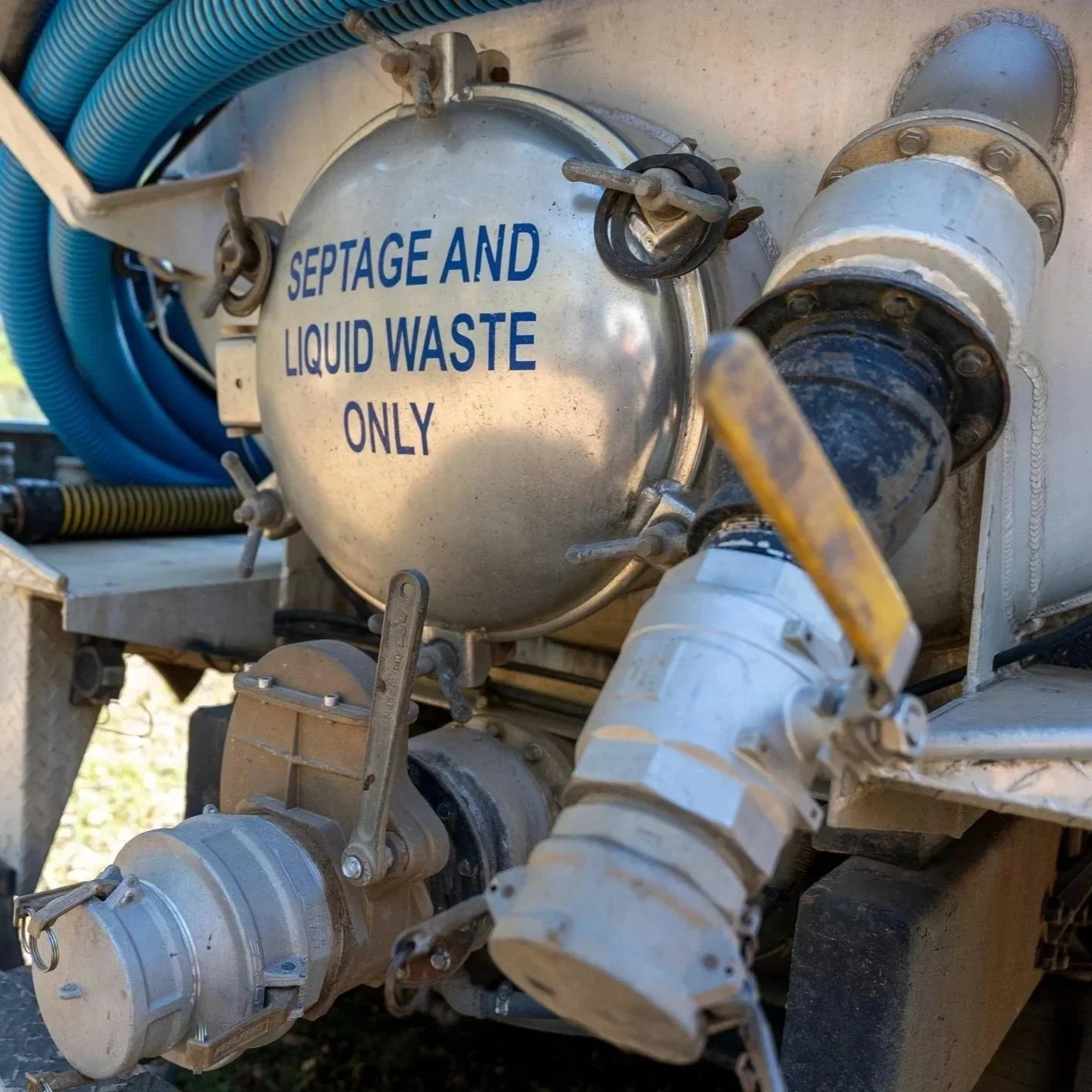 Close-up of septic vacuum truck fittings and liquid waste transfer connections used during residential and commercial septic pumping service operations.