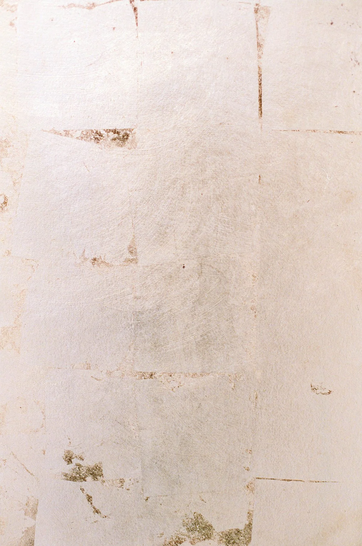Close-up of a textured, stained, and weathered light-colored wall with peeling paint and patches of discoloration.
