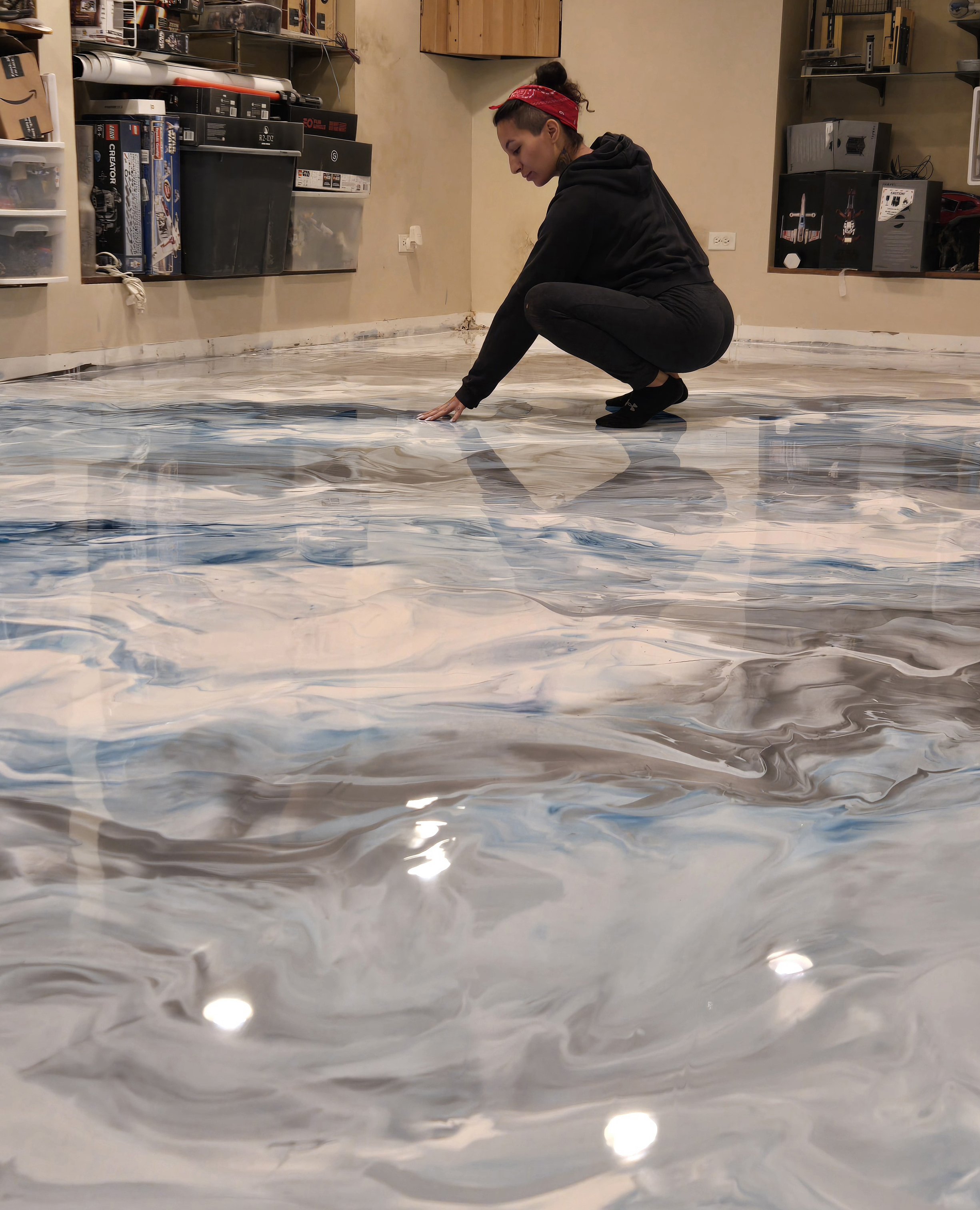 Woman in black hoodie and pants crouching on a marbled resin flooring.