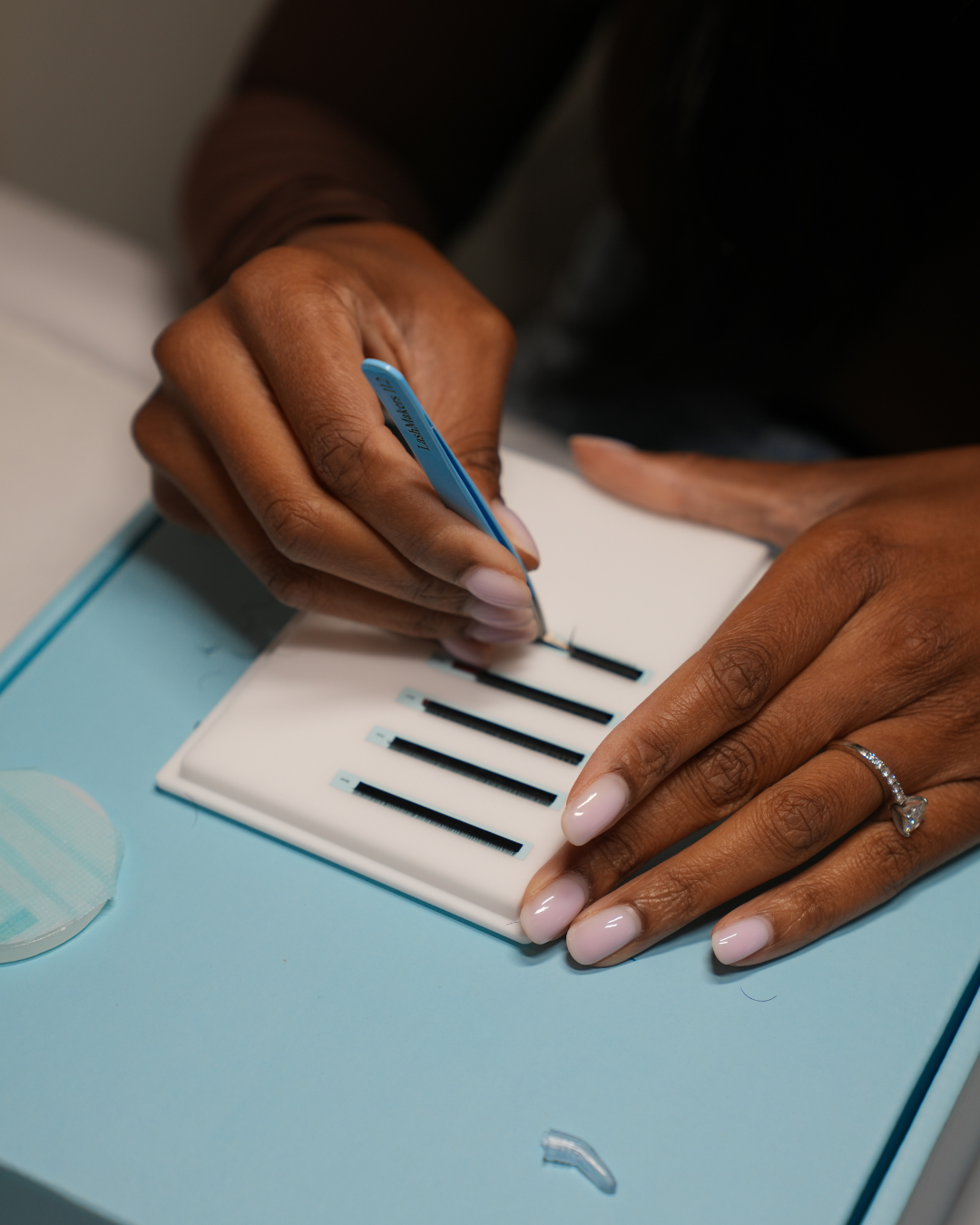 Person using a blue microblading pen to draw on eyebrows on a practice sheet with eyebrow templates.