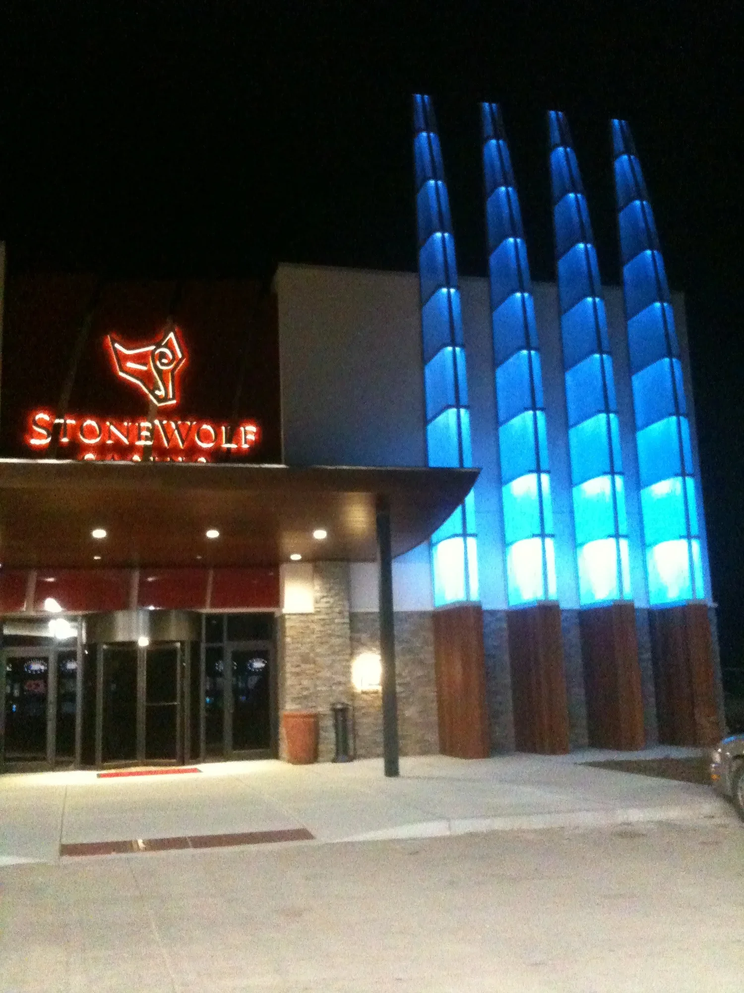 Nighttime exterior view of Stonewolf Casino with illuminated sign, entrance, and blue-lit architectural features.