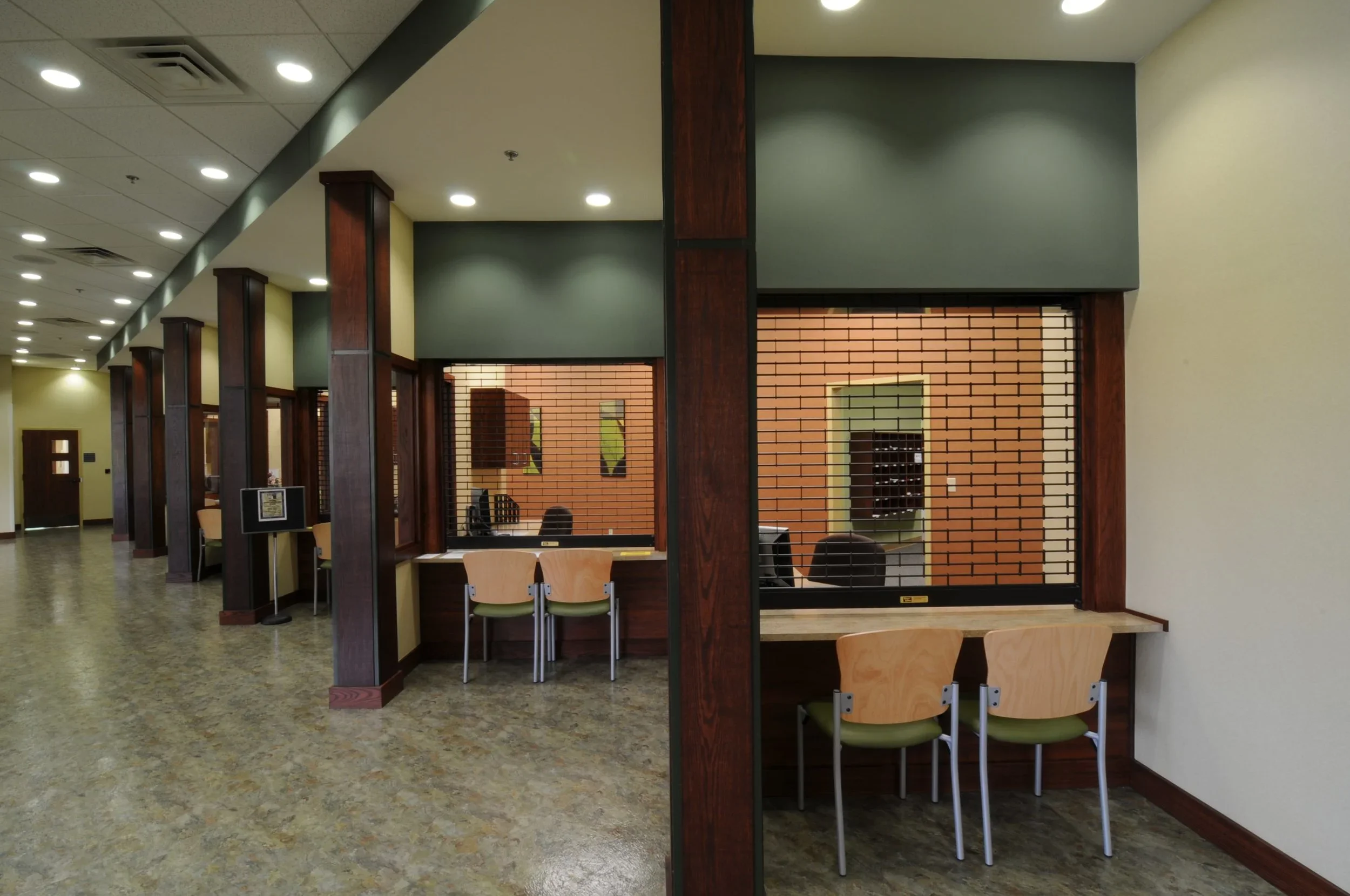 Empty office reception area with two sections separated by a divider, chairs, counters, and brick walls.