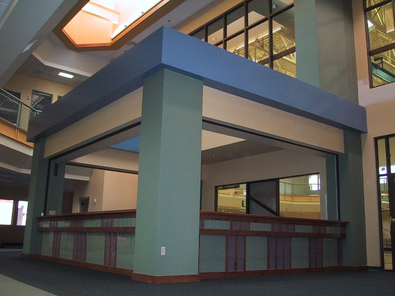 Interior of a modern, multi-level building with a blue and beige structure, large windows, and metallic railings.