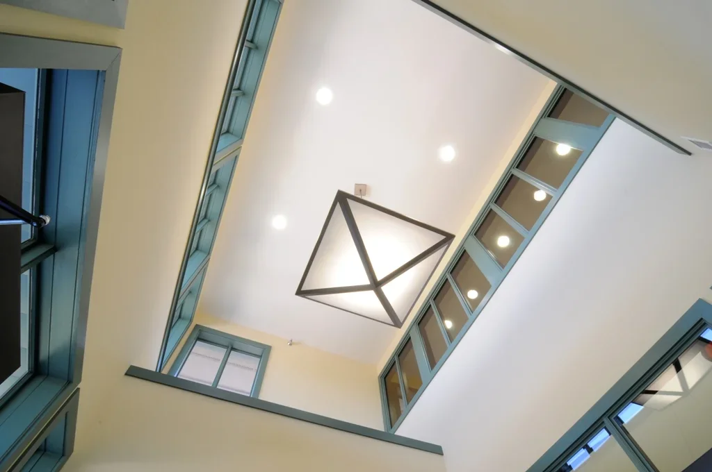 View of a modern interior courtyard with glass windows and a geometric chandelier hanging from the ceiling.
