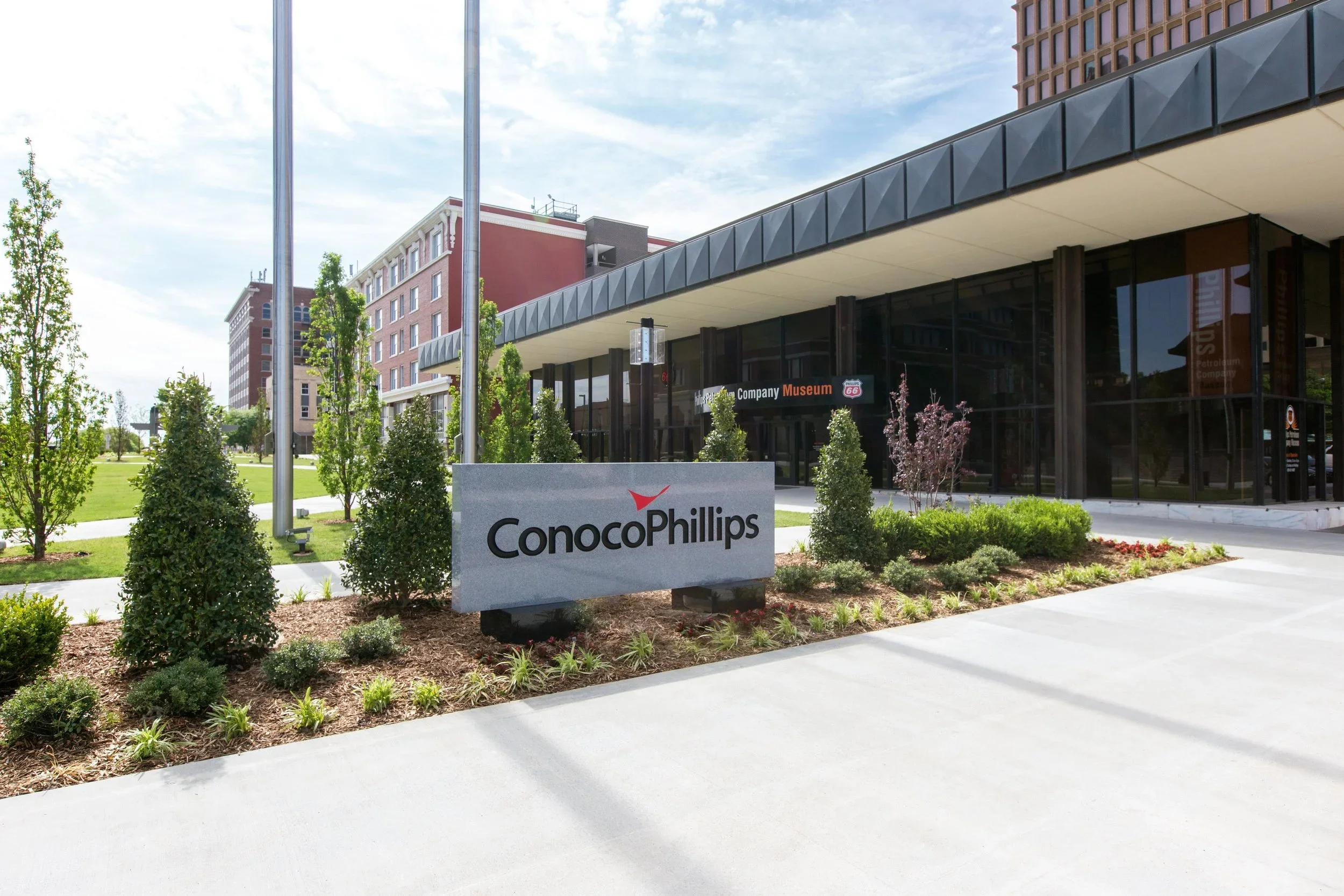 ConocoPhillips corporate sign in front of a modern building with mature greenery and a museum entrance