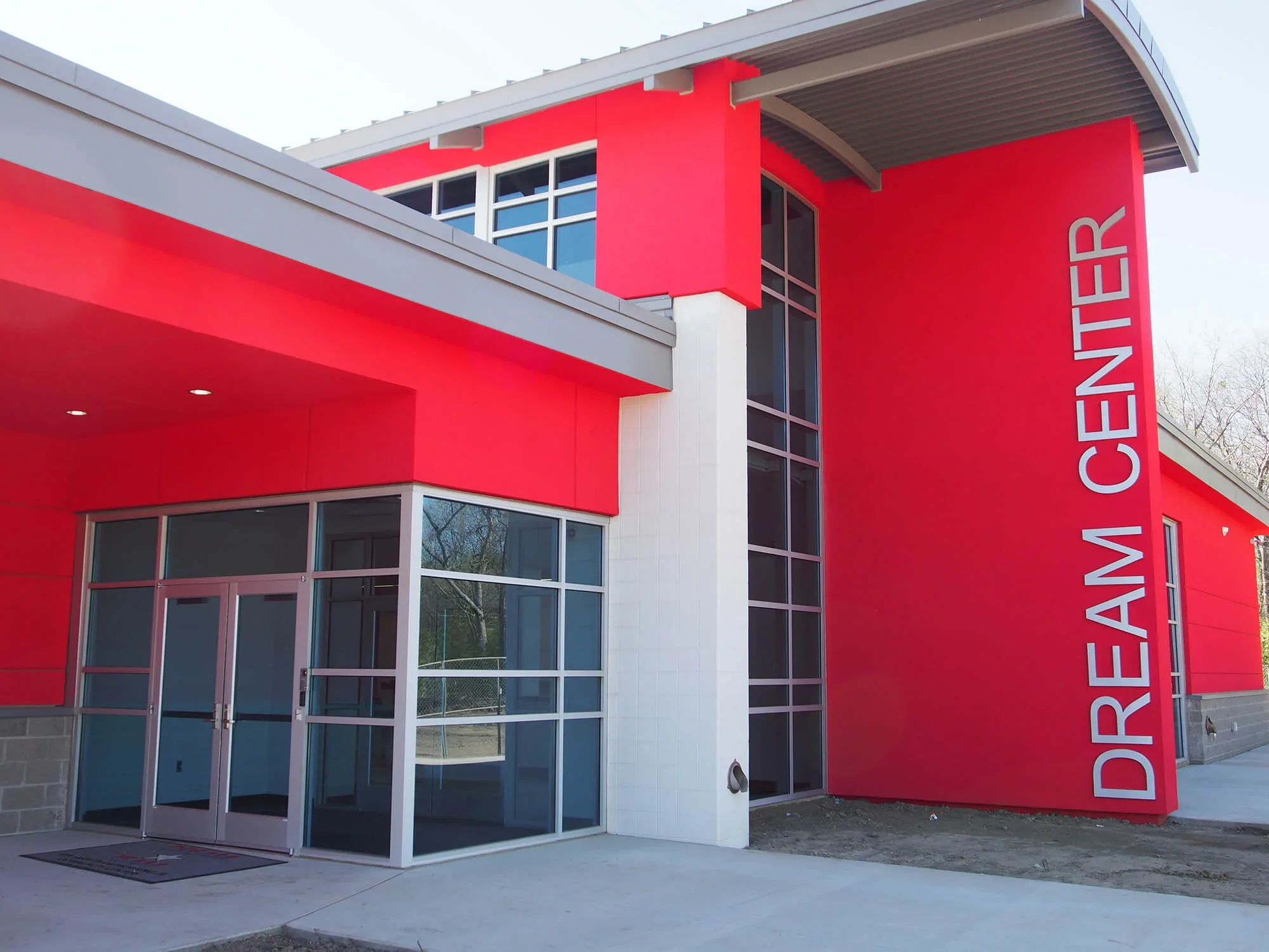 Modern red and white emergency center building with large vertical sign reading 'DREAM A CENTER' on the exterior wall. Glass doors at entrance and large windows.