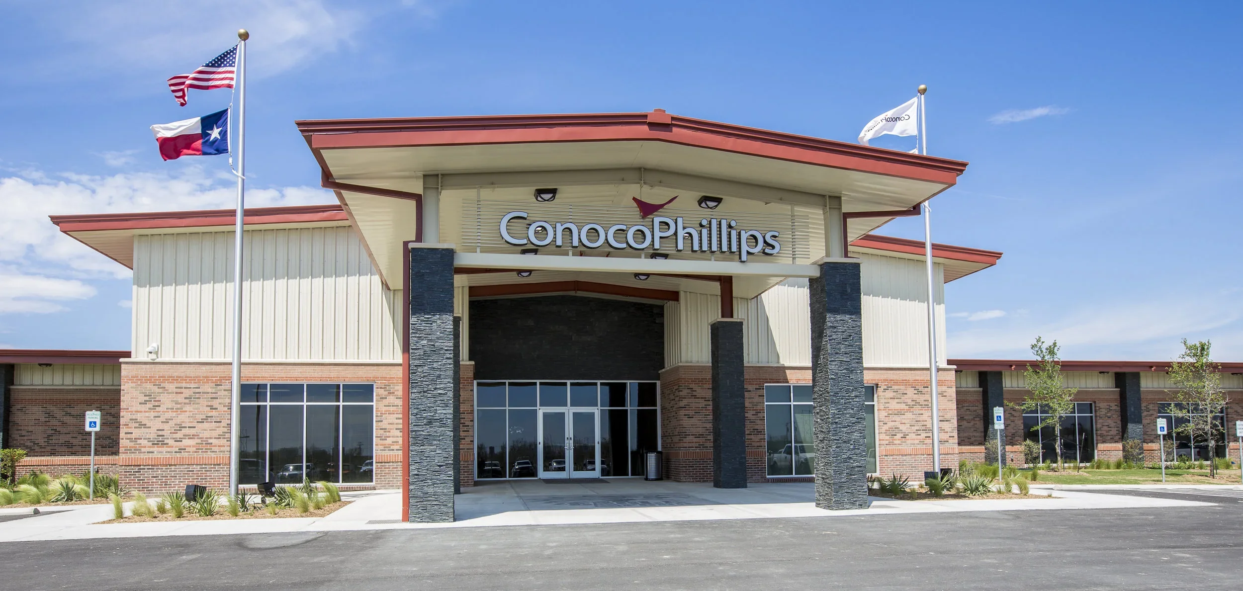 ConocoPhillips office building with flags, brick and siding exterior, and a clear blue sky.