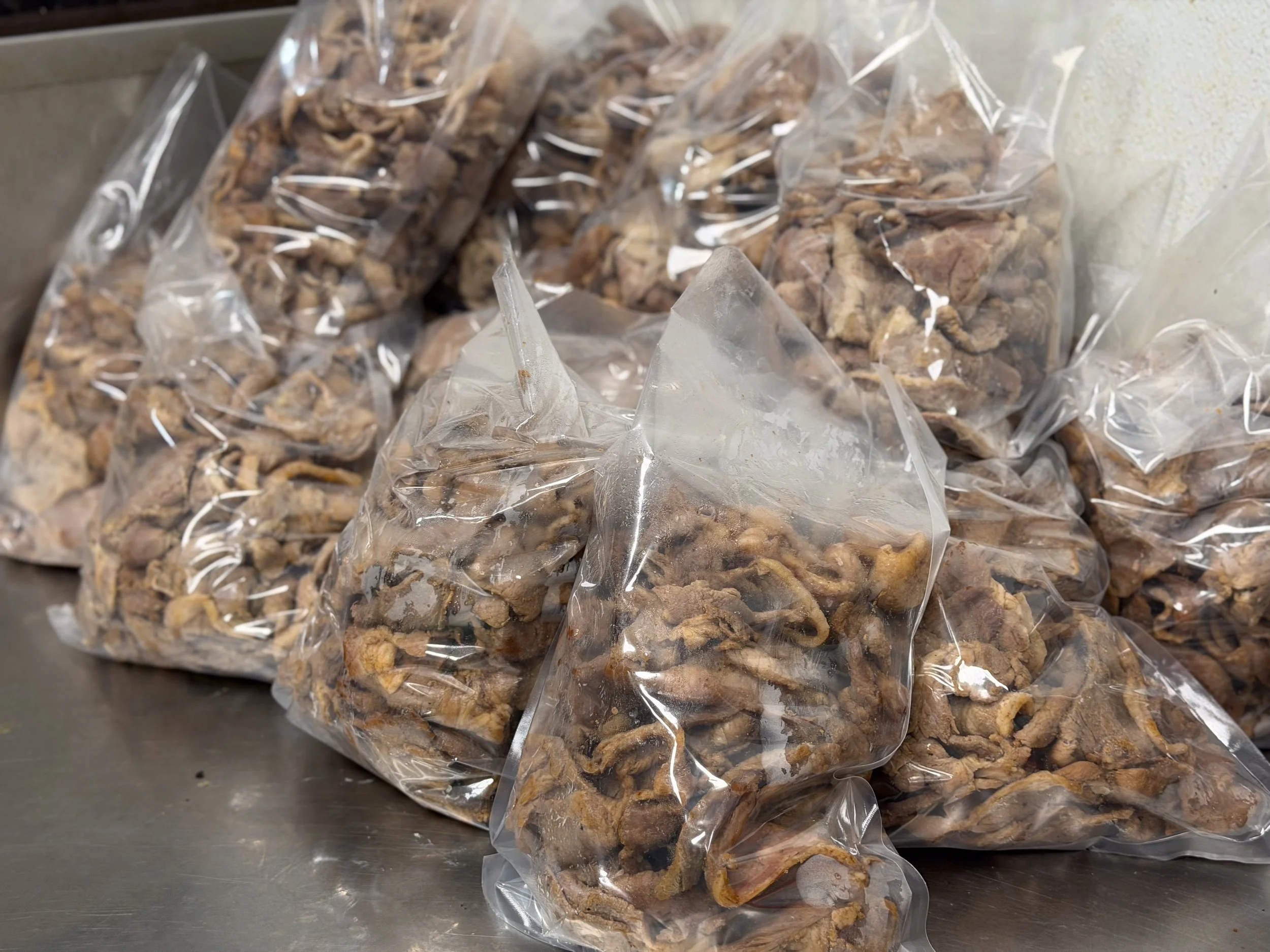 Multiple clear plastic bags filled with dried animal organs or meat on a stainless steel surface.