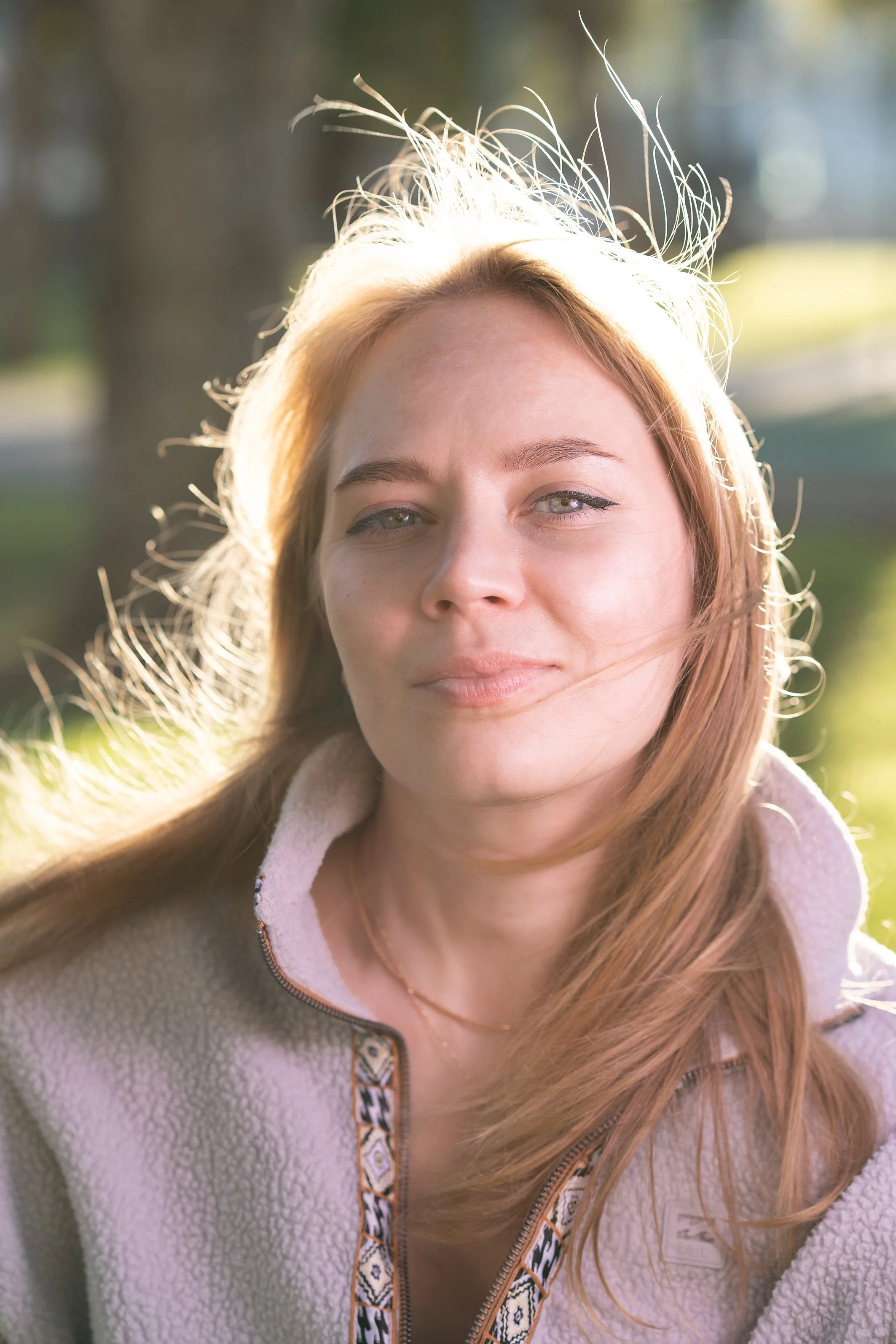 young woman on nature background smiling, her face and hair shining with sunlight