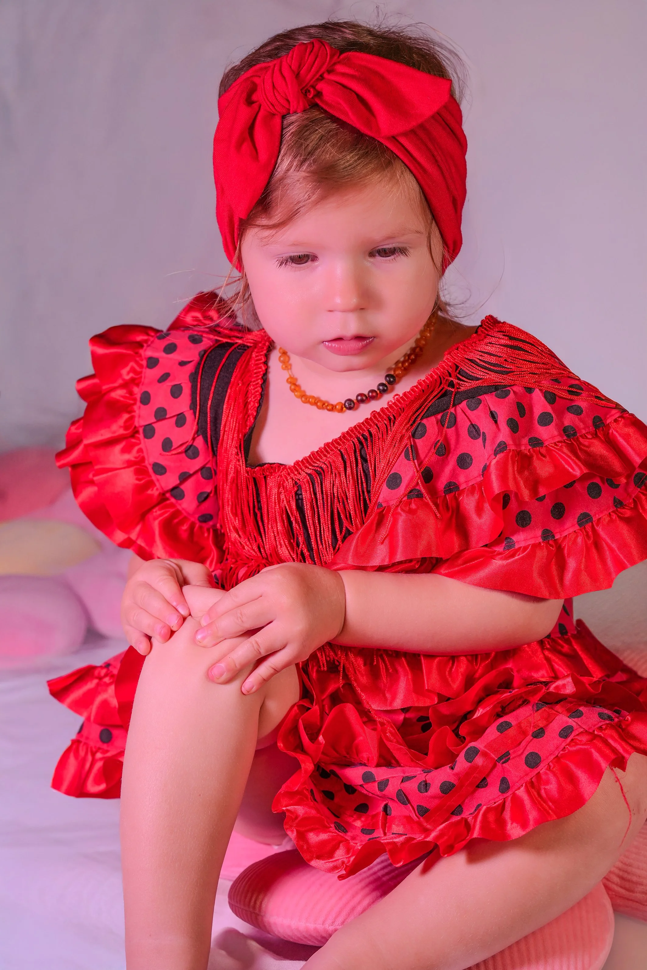 Baby girl ,wearing red dress and red hair band, sitting and watching cartoons 