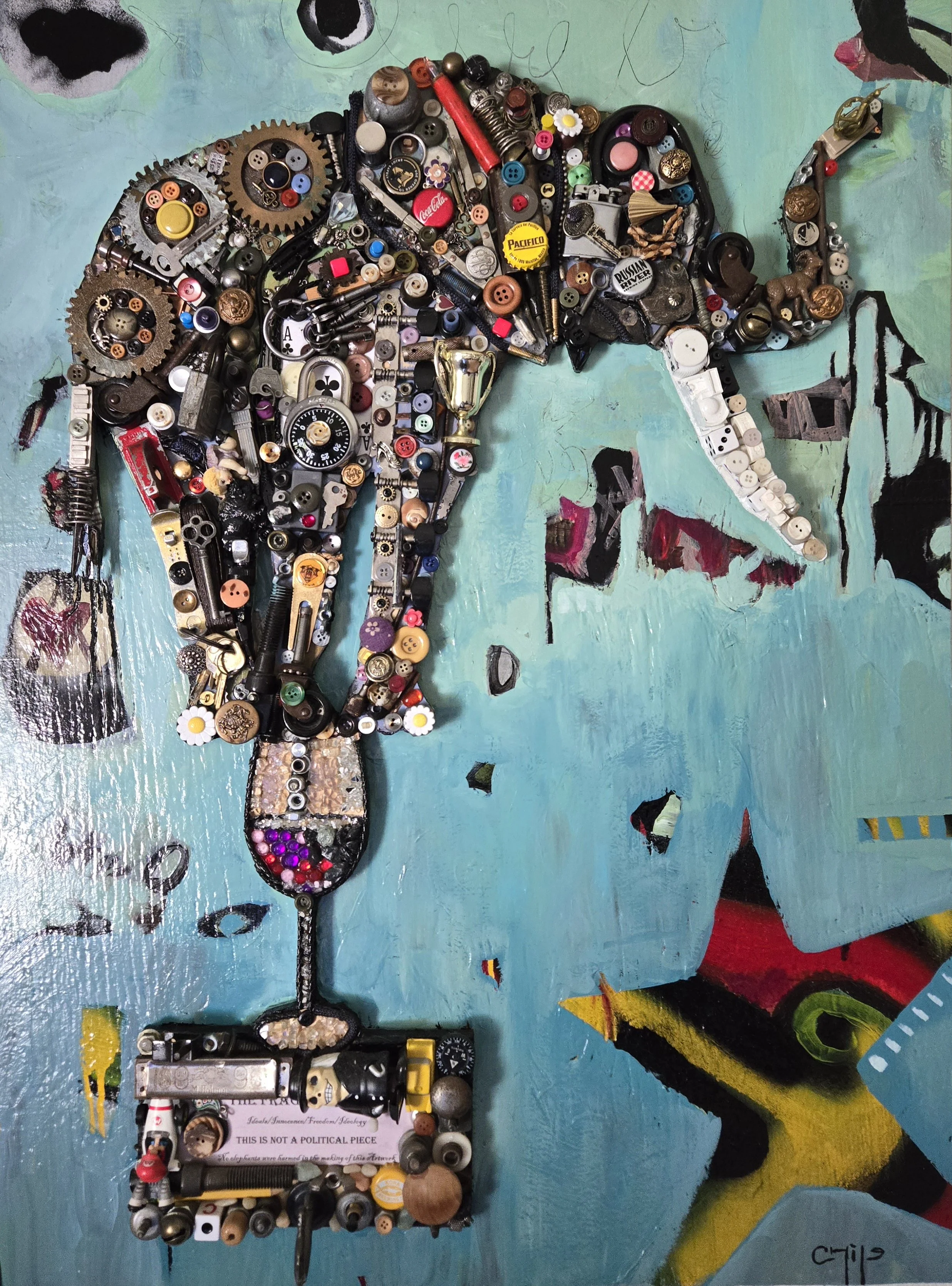 A collage art piece consisting of various small objects such as buttons, screws, and electronics arranged to form the shape of a hammer and a blood drop, mounted on a colorful painted background.
