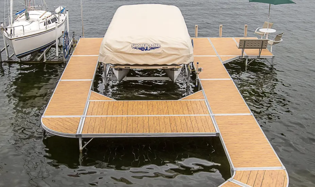 Dock with a pontoon boat covered with a beige tarp, and two smaller boats, one to the left and one to the right, on a lake.