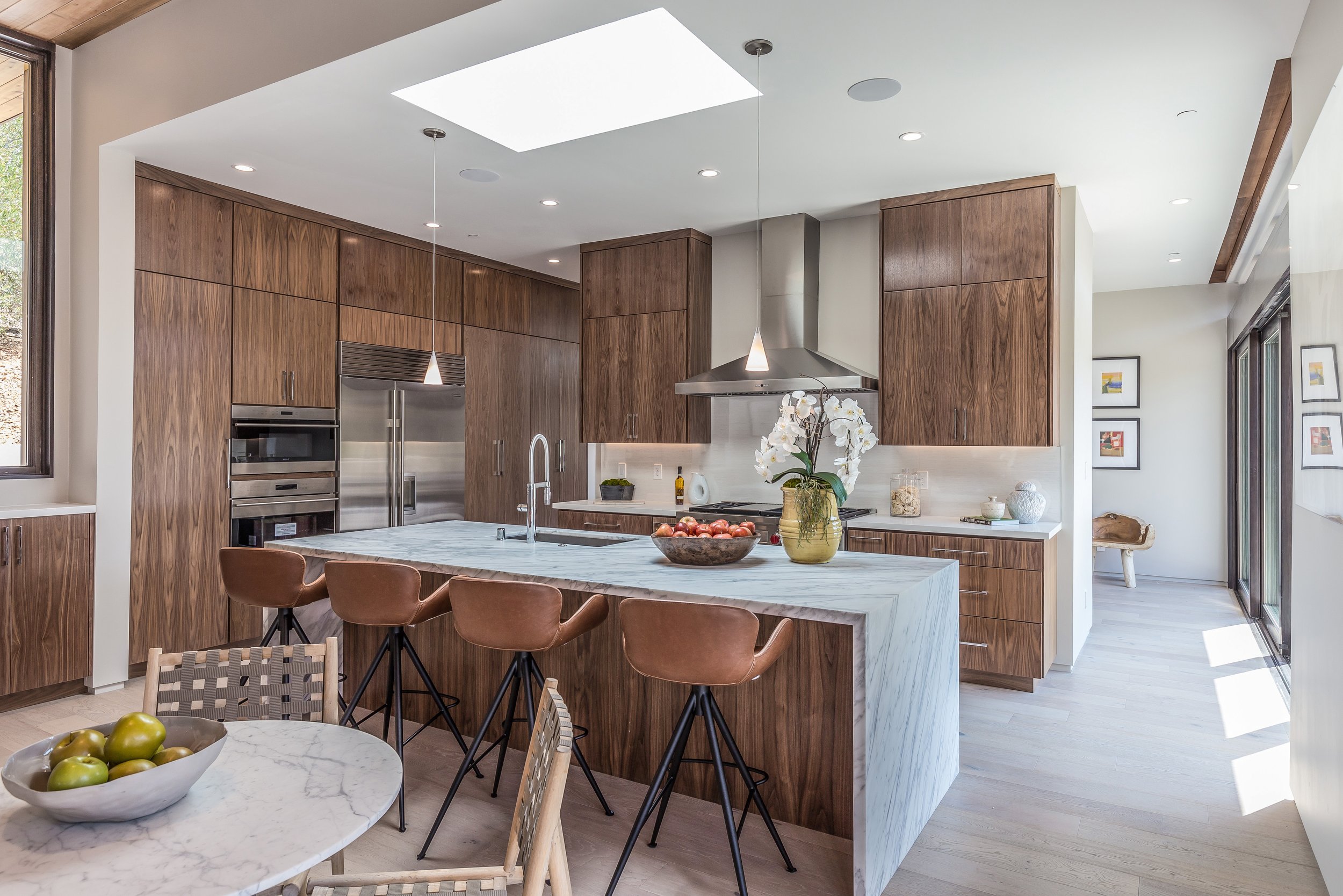 Los Altos Hillside Home in Los Altos, California. Modern kitchen with wooden cabinets, marble island, and stainless steel appliances.