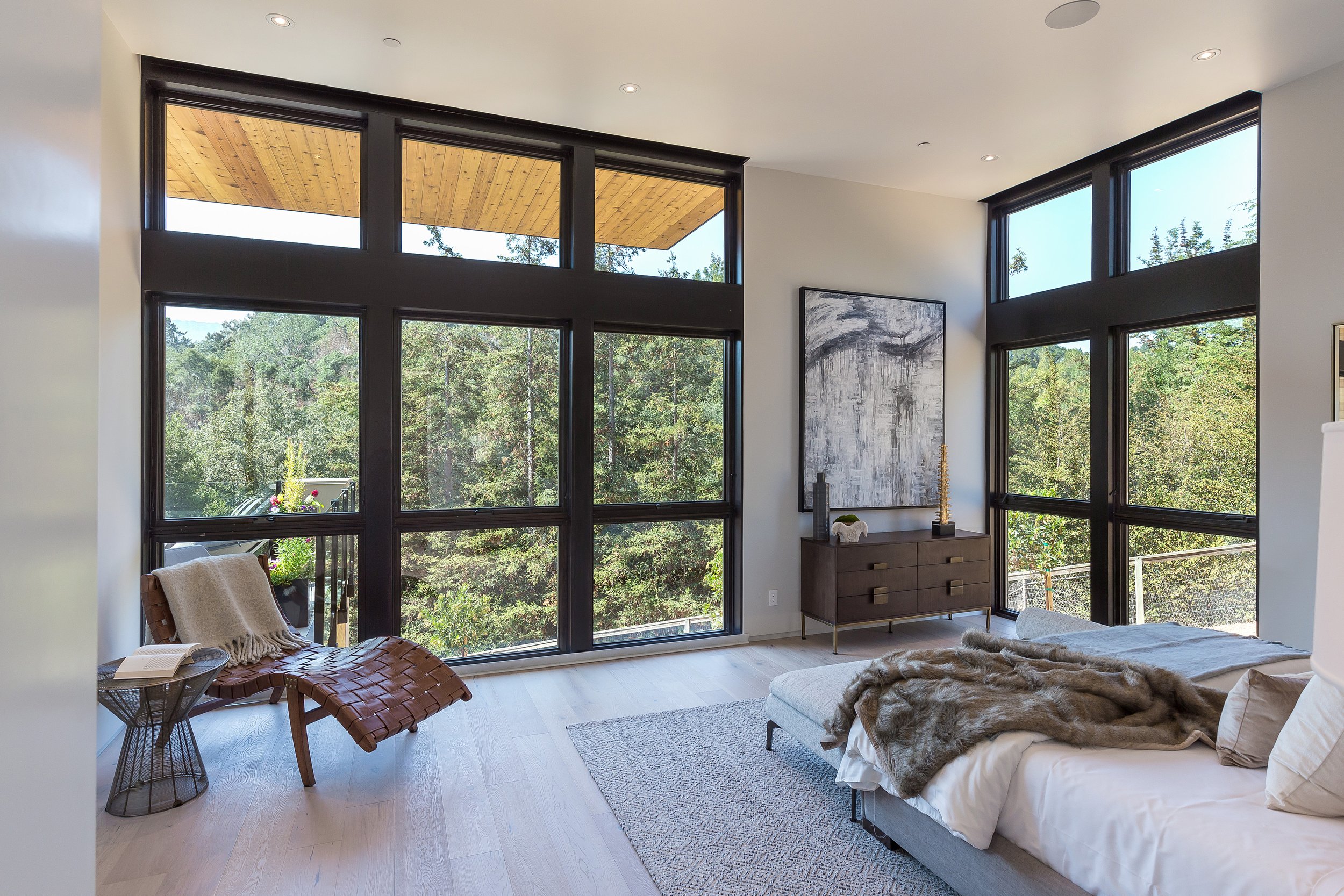 Los Altos Hillside Home in Los Altos, California. Modern living room with large windows showing a forest view.