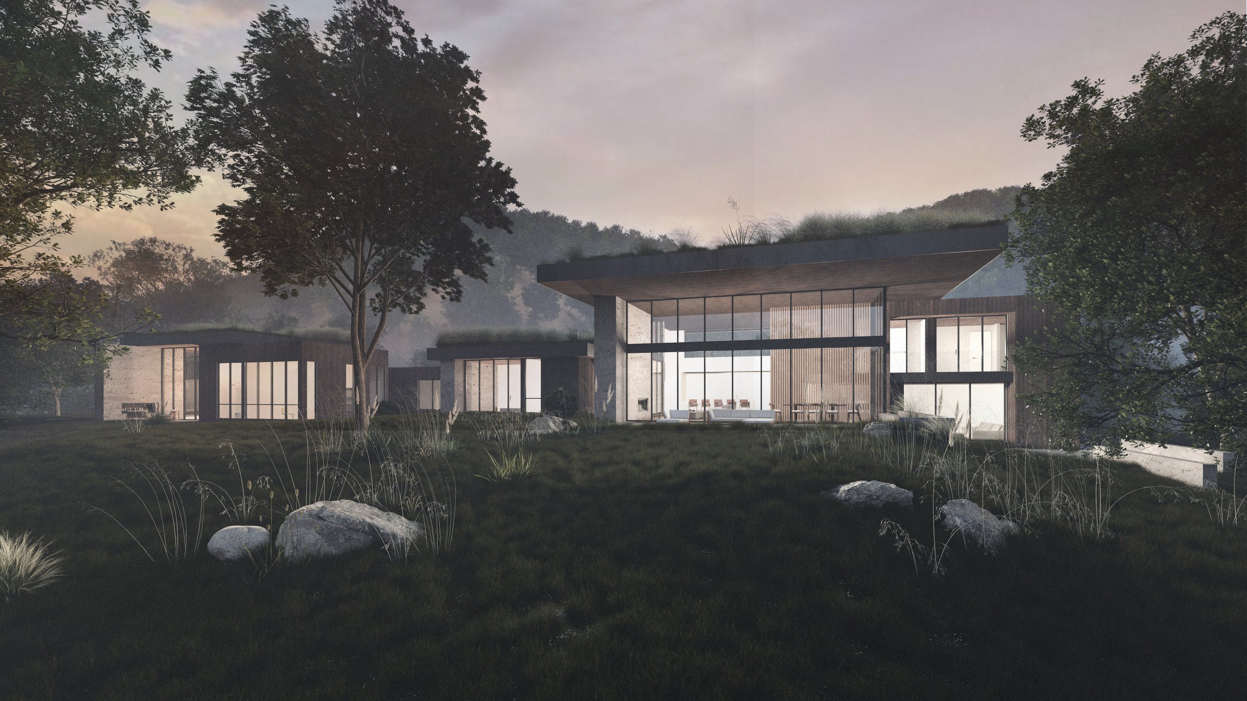 Carmel Valley Retreat Home in Carmel, California. Modern cabin-style house with large glass windows, surrounded by trees and rocks, during dusk or dawn.