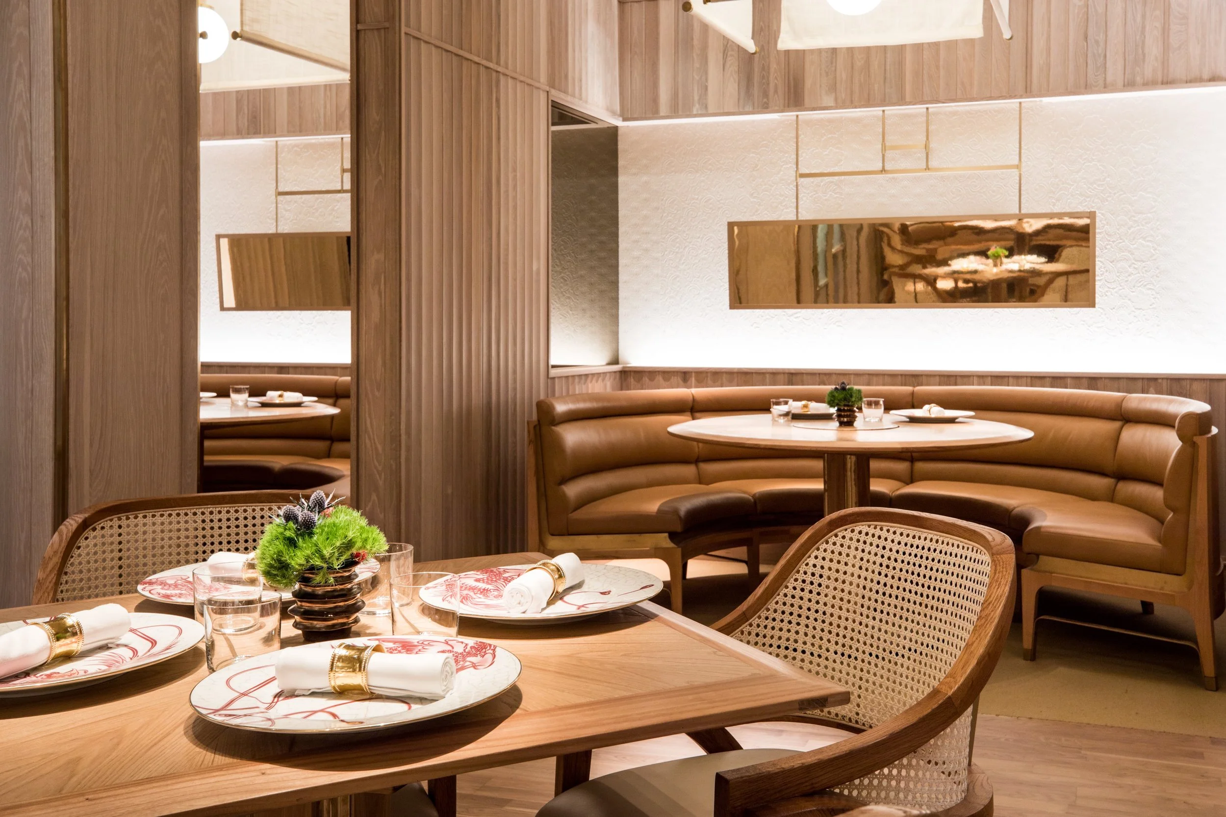 Eight Tables restaurant above China Live Market in San Francisco, California. A cozy restaurant interior with wooden decor, round tables set with plates, glasses, napkins, and a small green plant centerpiece.
