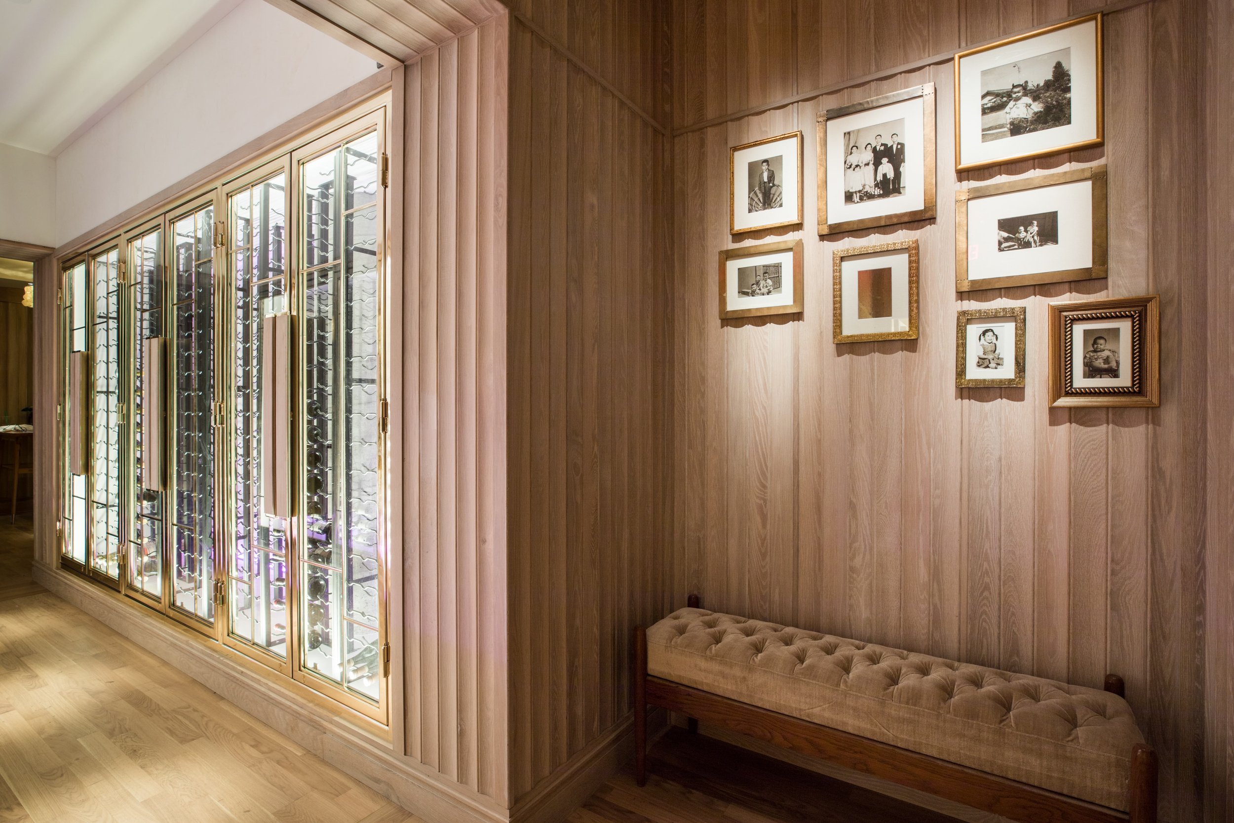 Eight Tables restaurant above China Live Market in San Francisco, California. A corner of a room with a wooden wall decorated with several black-and-white family photographs in various frames.