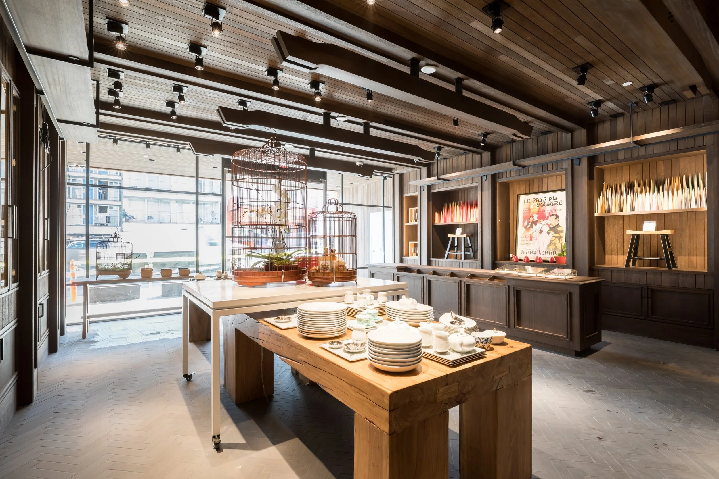 China Live Market in San Francisco, California. Experiential retail. Interior of a store with wooden walls and ceiling, displaying dishes and decorative items, with large windows allowing natural light.