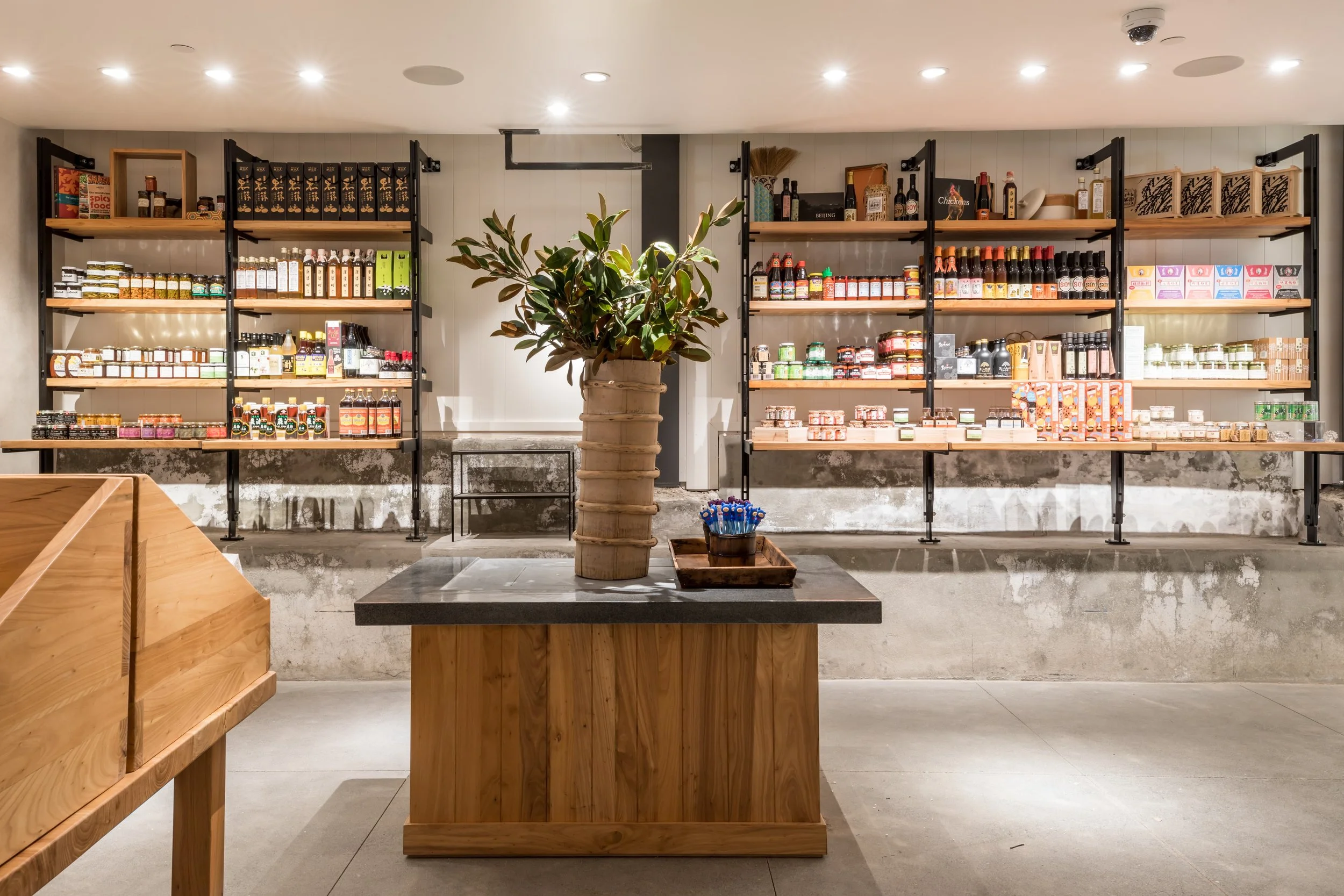 China Live Market in San Francisco, California. Experiential retail. Interior view of a store or cafe with wooden shelving filled with various jars, bottles, and packaged food products.