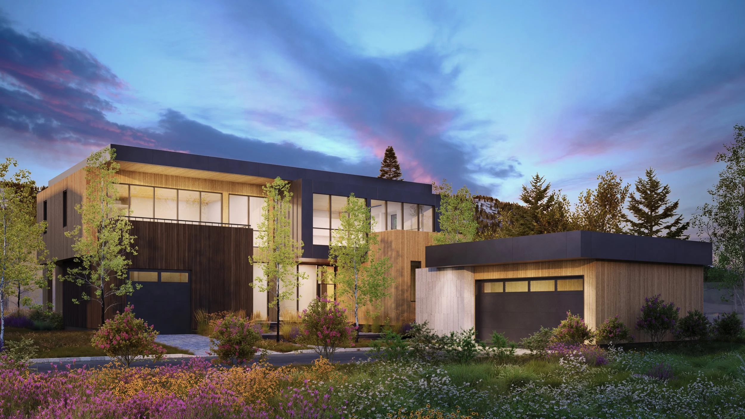 Jackson Development in Jackson, Wyoming. Modern house with large windows and a flat roof, surrounded by trees and colorful flowers, under a sky with clouds at sunset.