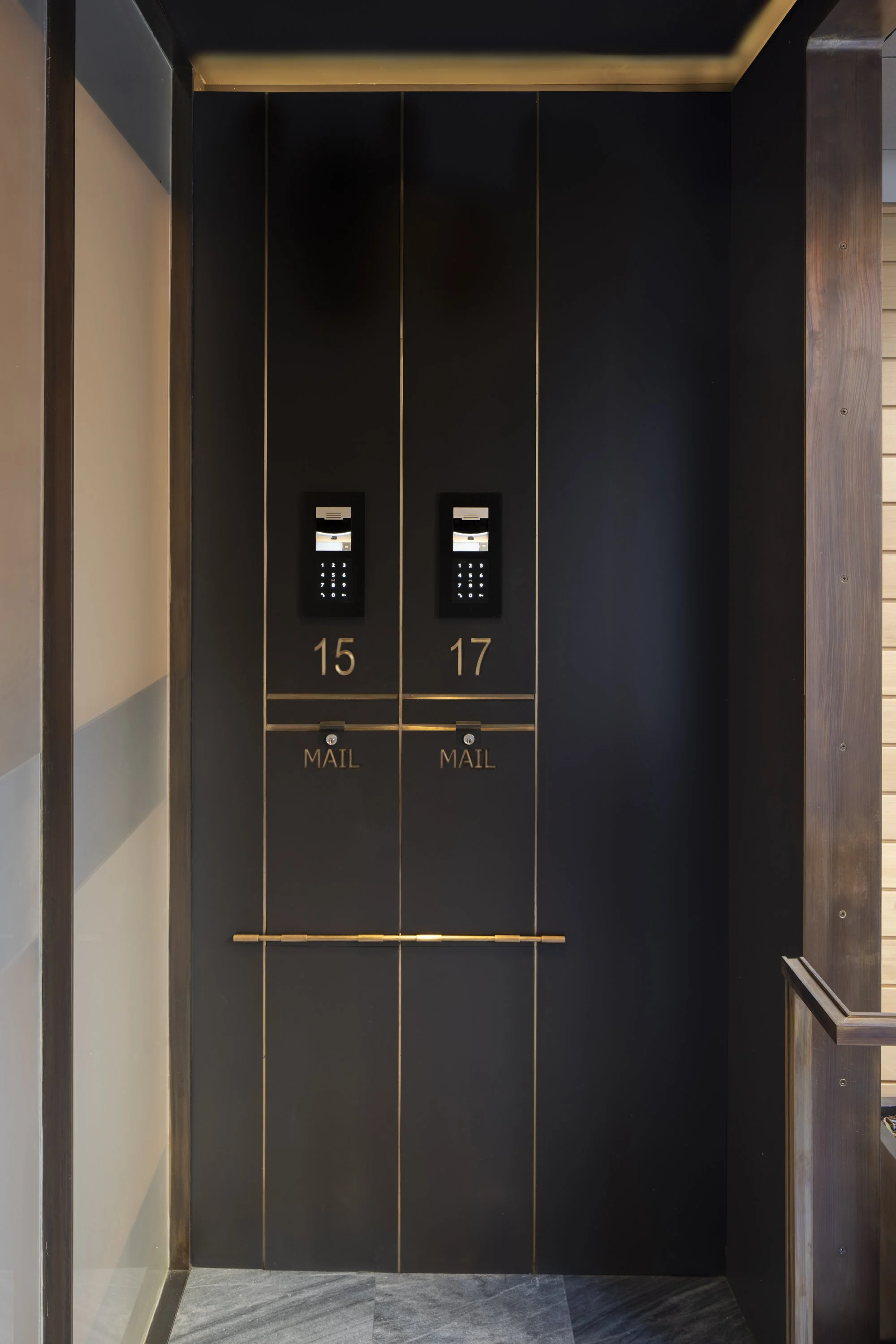 Six-Story-City House in San Francisco, California. Black elevator interior with wood accents and keypad panels labeled 15 and 17, with mail slots underneath.