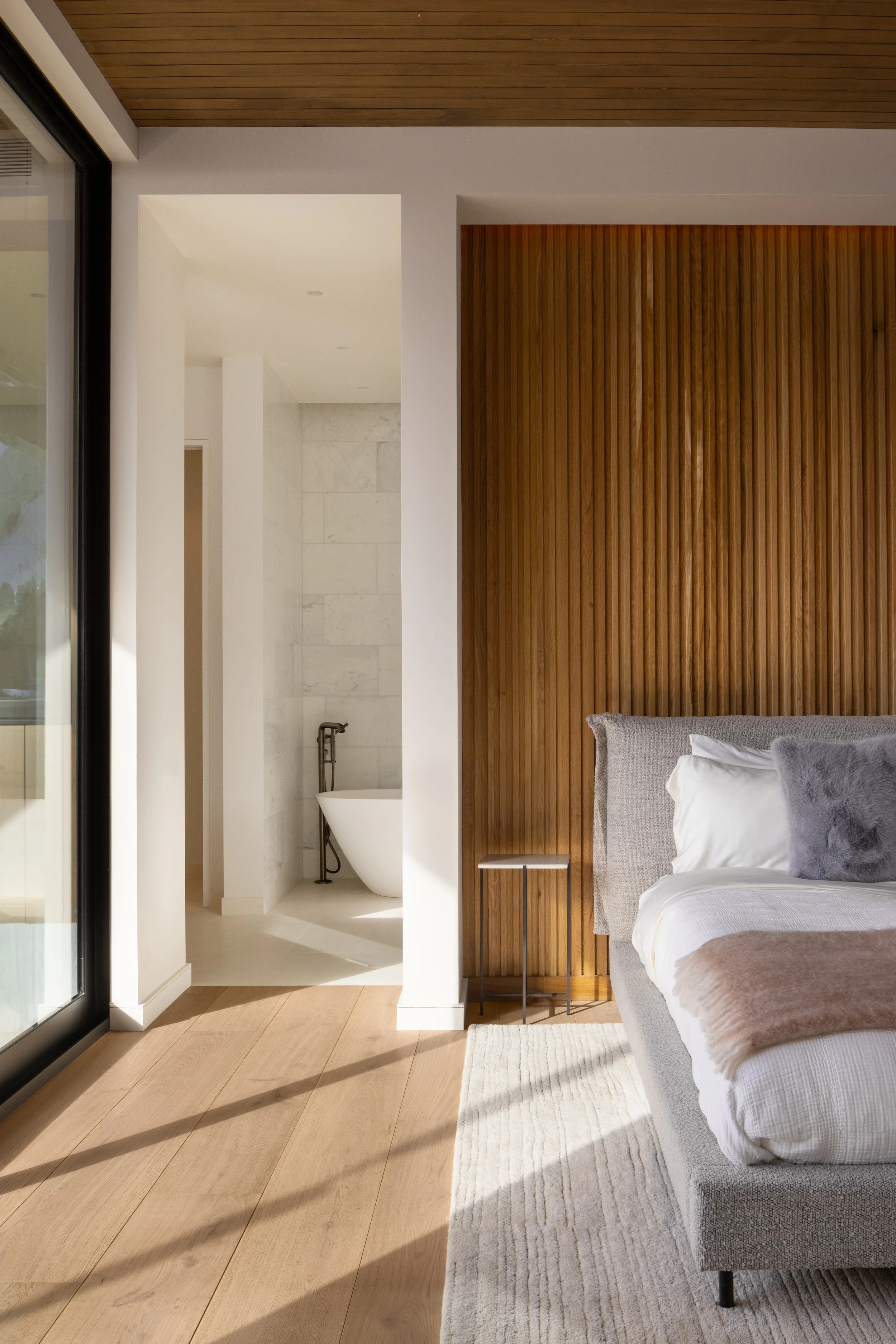 Grand Teton House in Jackson, Wyoming. A modern bedroom with a bed, pillows, and a beige blanket.