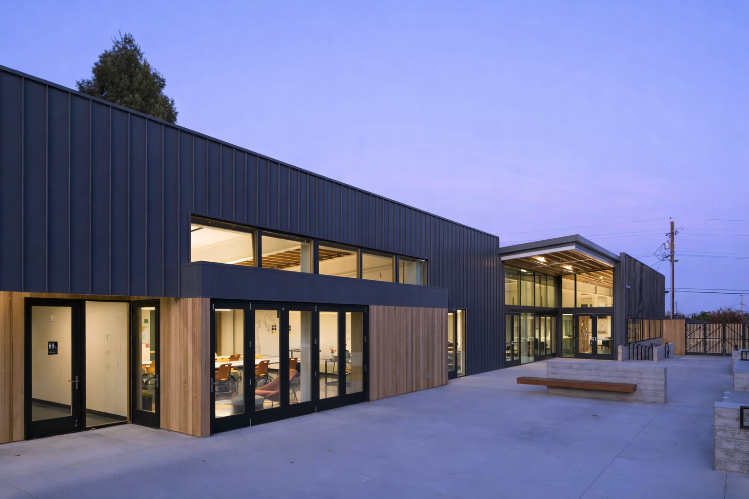 Spring Hill Montessori in Petaluma, California. A STEAM-focused campus designed for flexibility, connection, and real-world learning. Modern educational or community building with large windows and wood accents, illuminated at dusk.