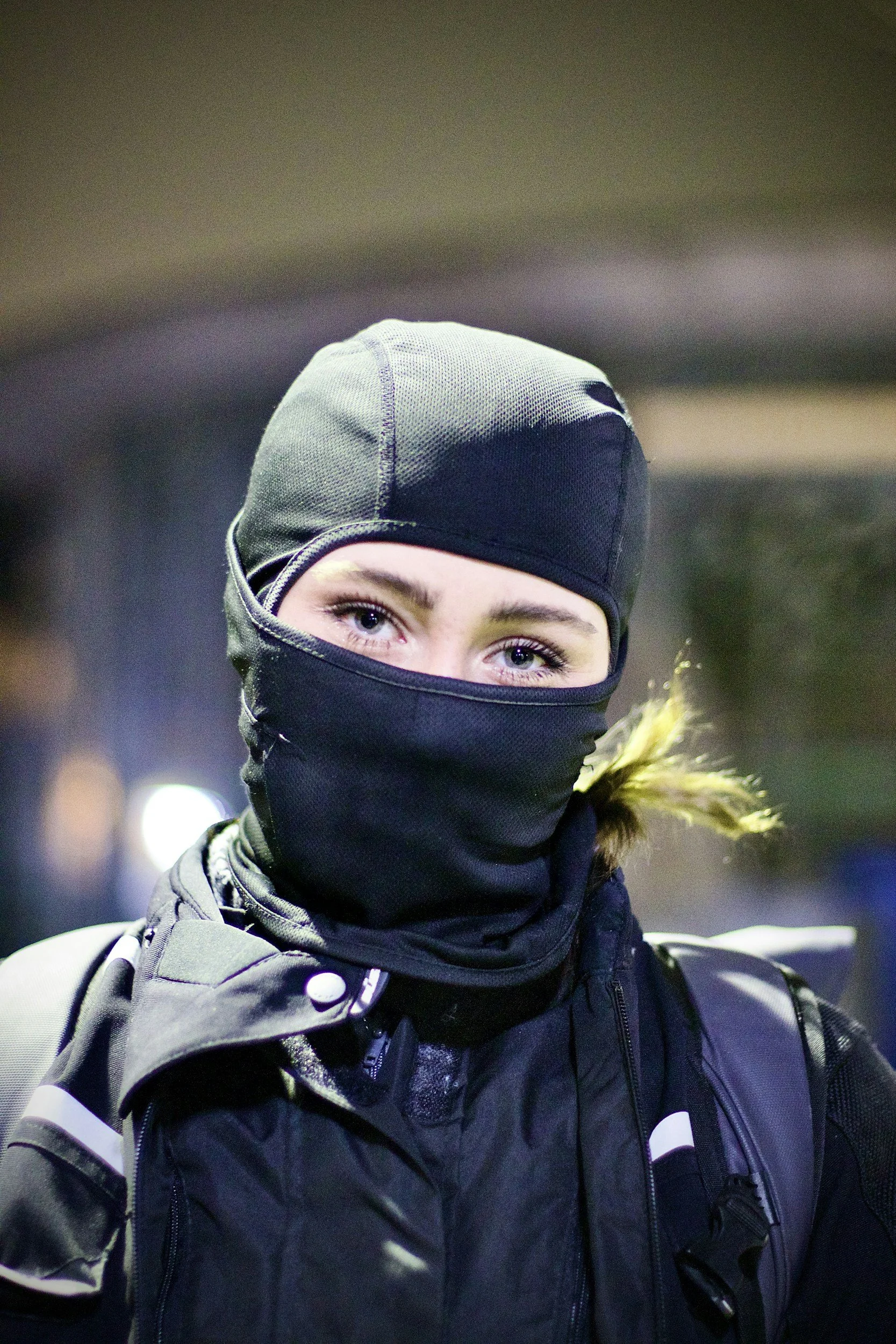 Person in dark clothing covering their face, suggesting secrecy or a narrow escape