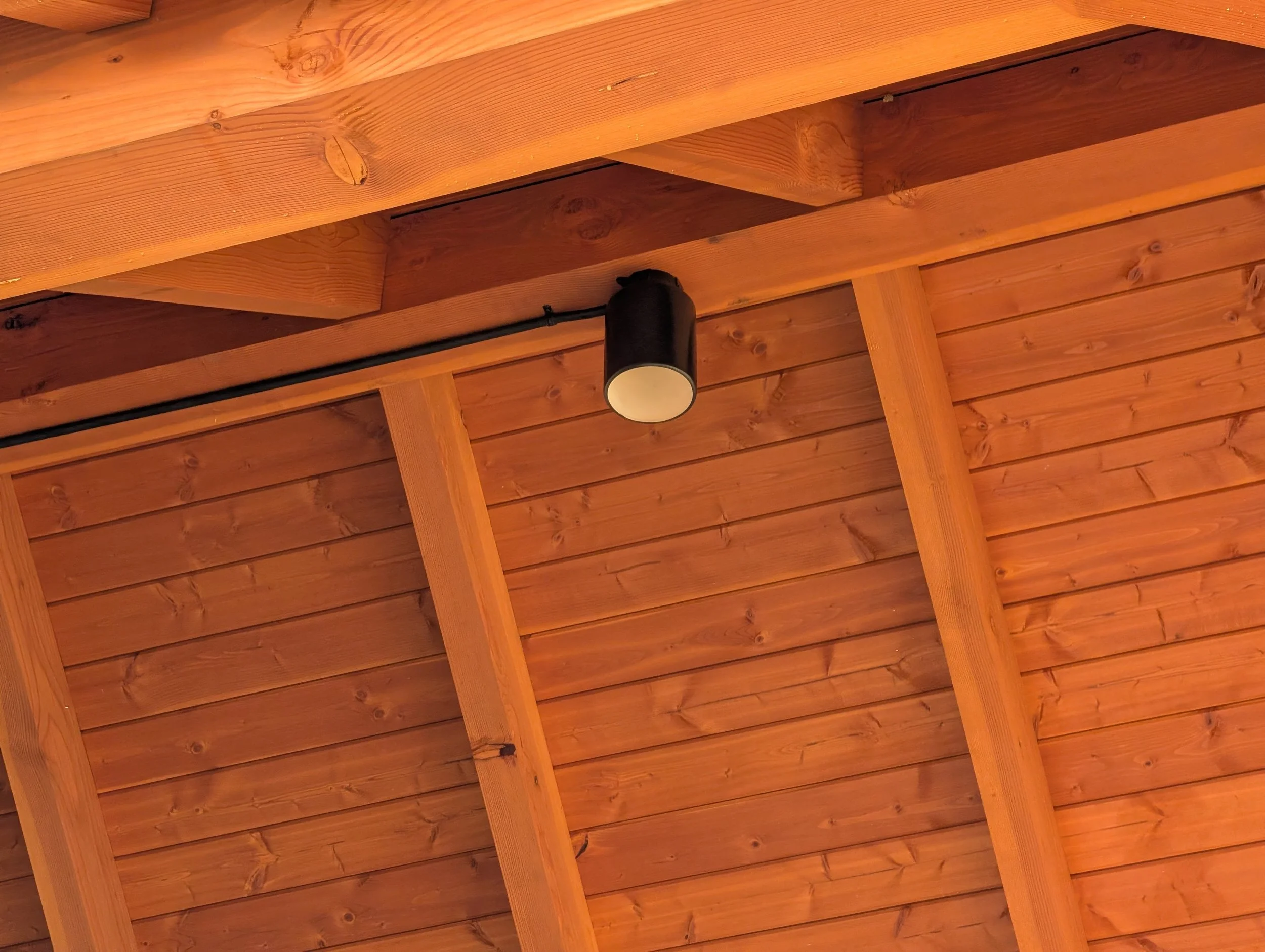 Wooden ceiling with exposed beams and a ceiling light fixture.