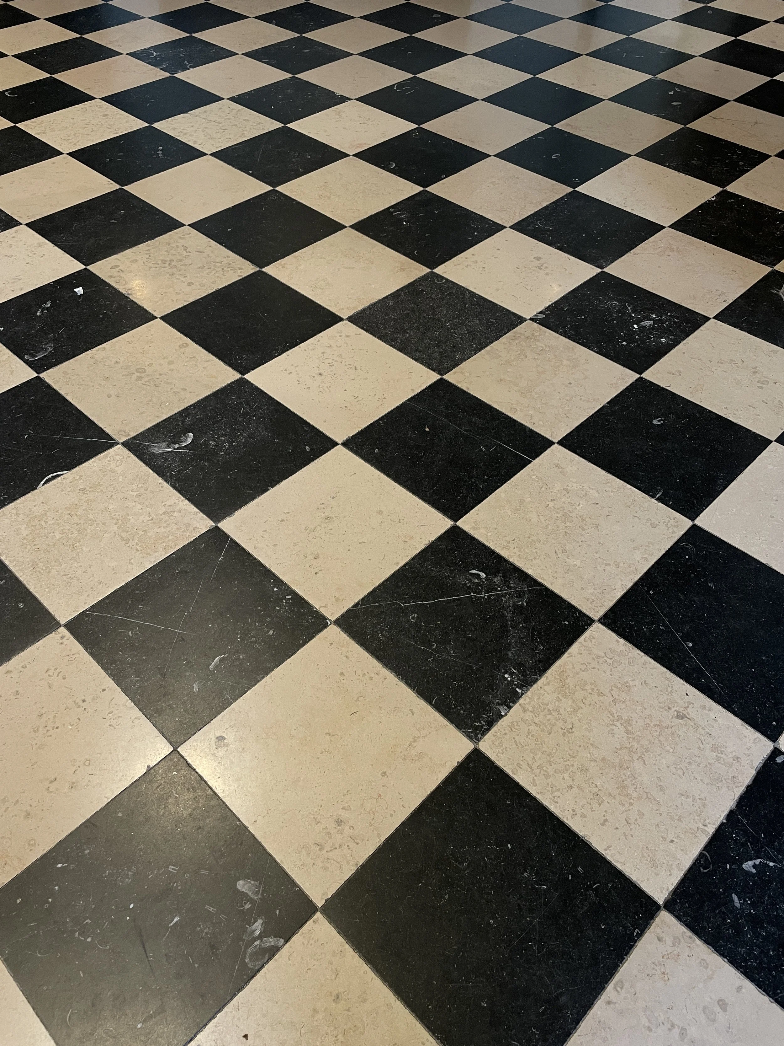 Checkerboard black and beige tiled floor with some dirt and scuff marks.