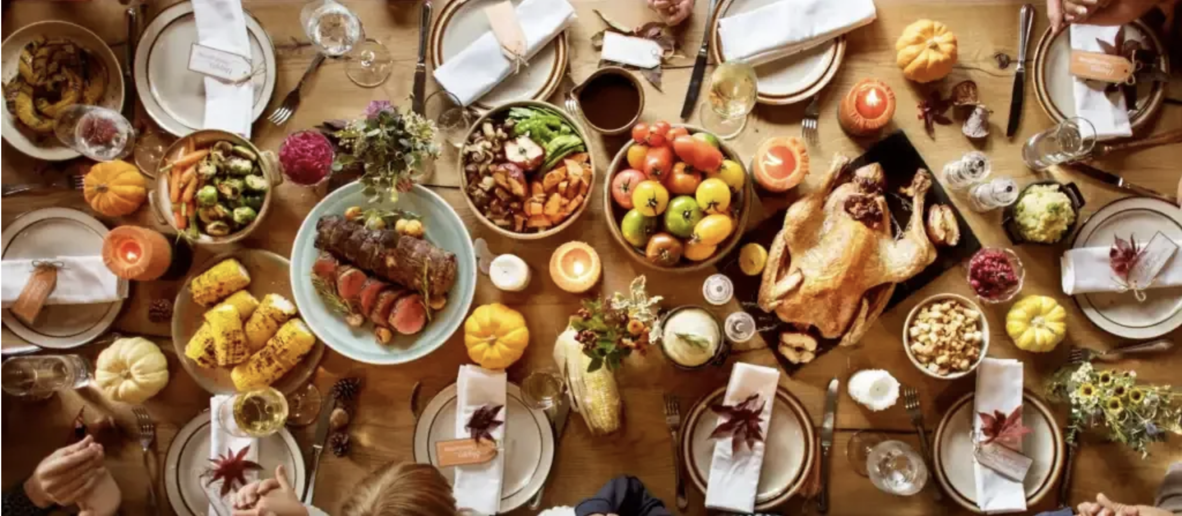 A holiday table full of different kinds of food with several place settings