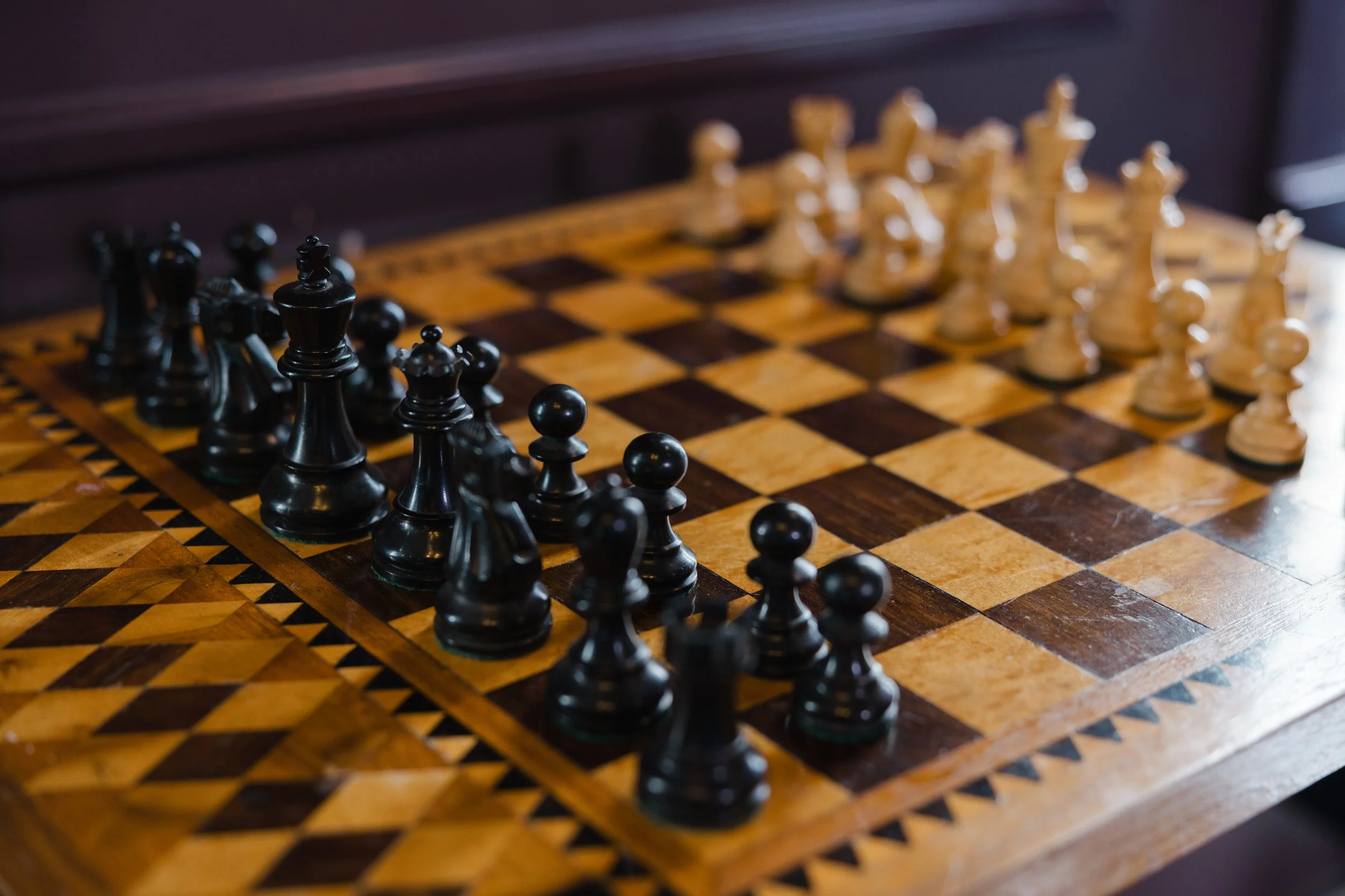 A chessboard with black and white chess pieces set up for a game.