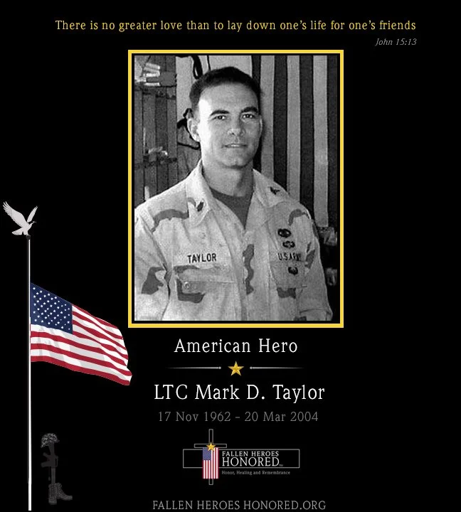Grayscale memorial poster for LTC Mark D. Taylor, an American hero, with a photograph of him in military uniform. The poster features an American flag, a quote from John 15:13 at the top, and a fallen heroes honored logo at the bottom. It includes his birth and death dates and the website fallenheroeshonored.org.