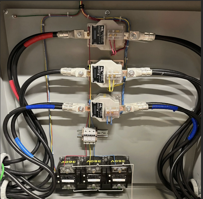 Electrical panel with circuit breakers, wiring, and large power cables.