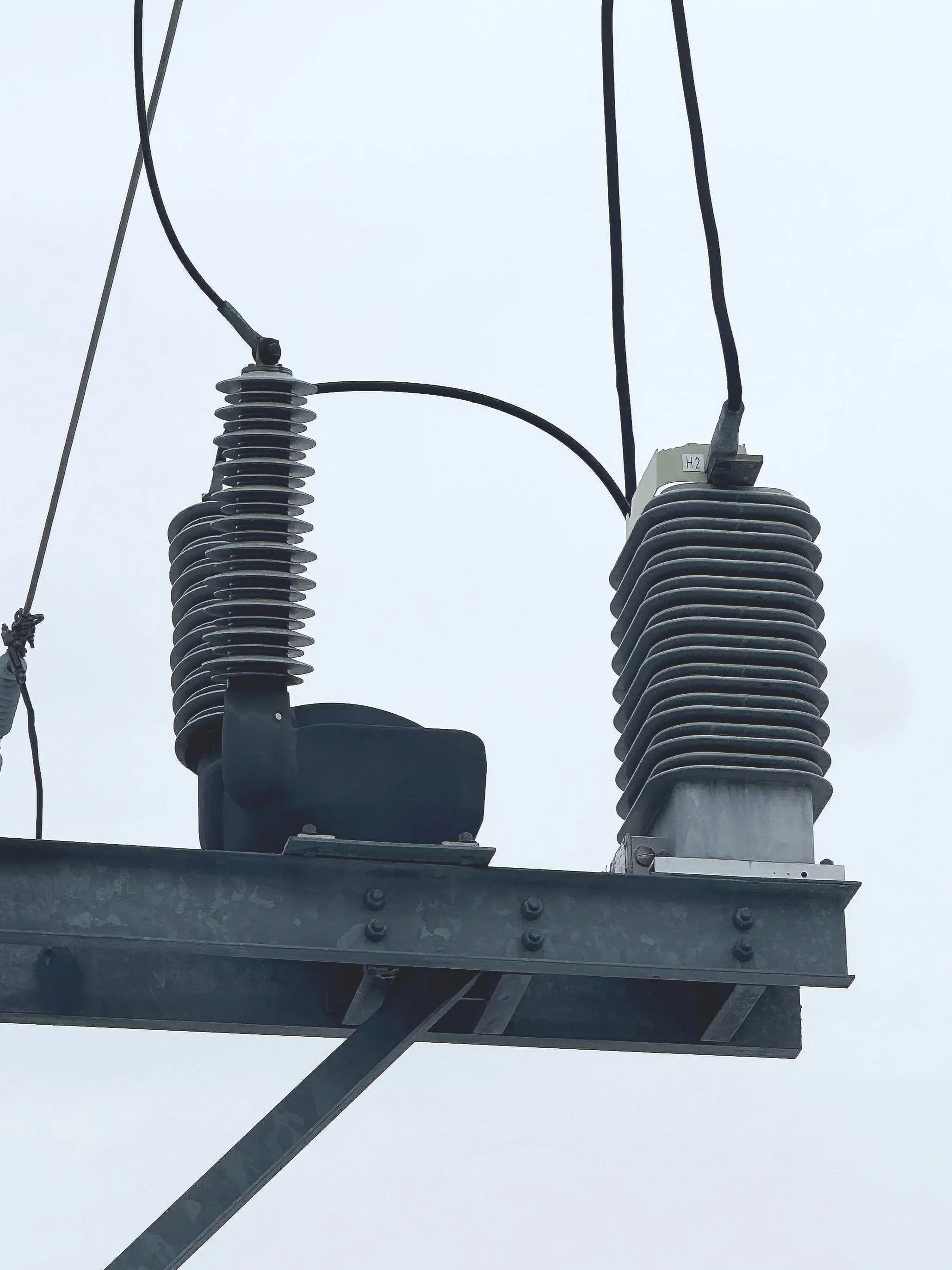 Close-up of electrical insulators and wires on a utility pole against a cloudy sky.