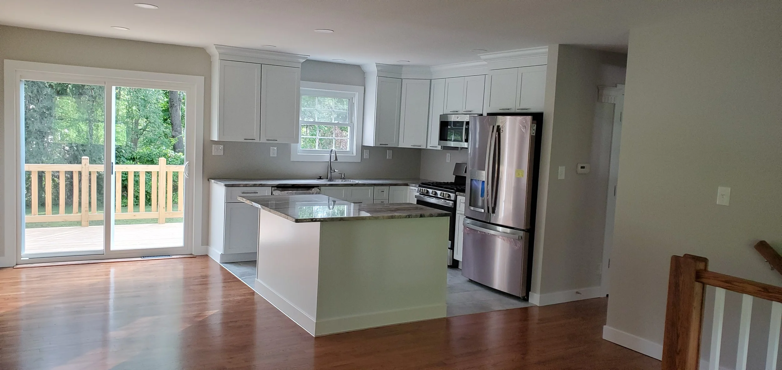 remodeled kitchen supporting wall removed new cabinets all around , stainless appliances quartz countertop refinished oak floors , stainless steel refrigerator, oven, microwave, and a center island with a quartz countertop. new sliding glass door lea