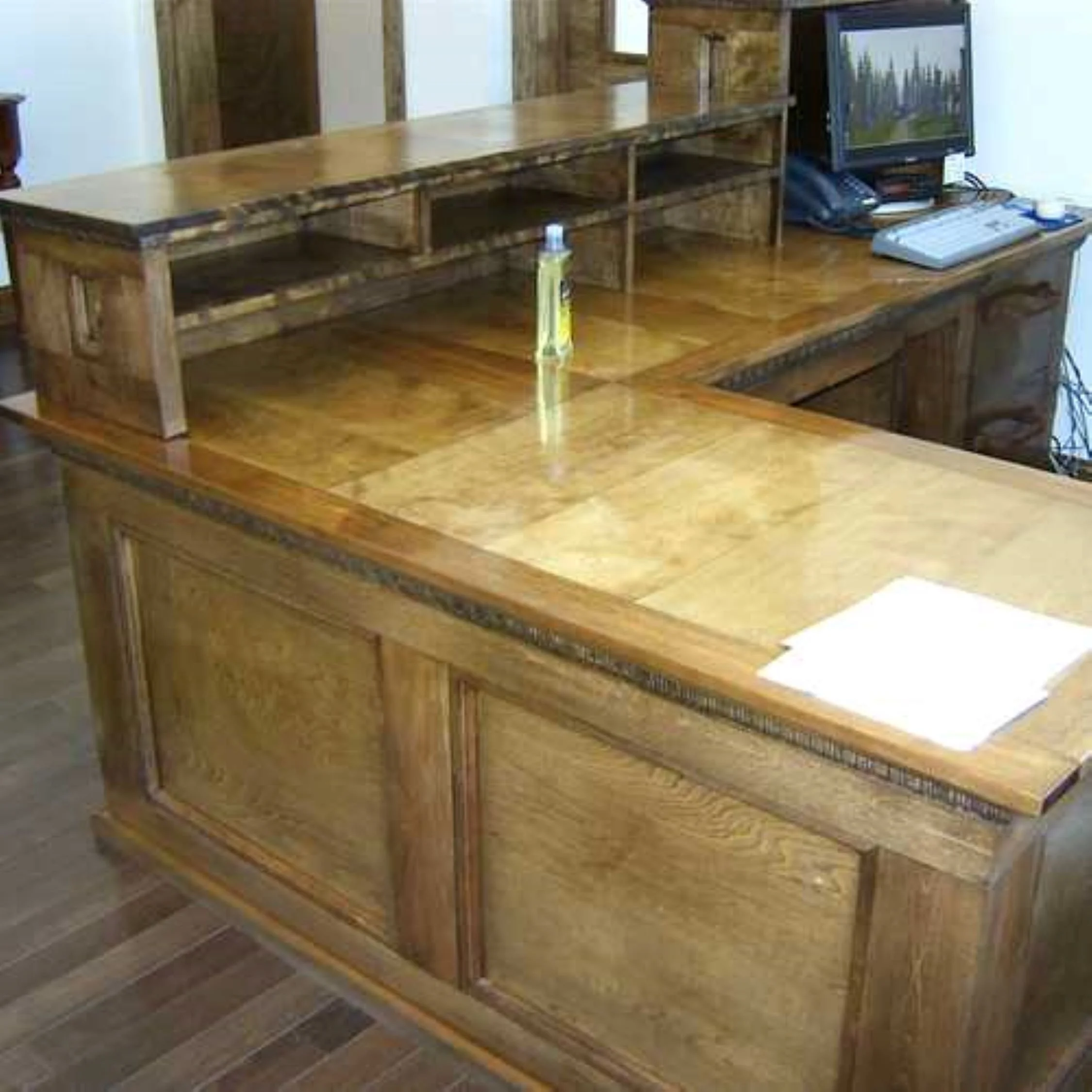 A large wooden desk with a hutch and a computer, phone, and papers on it.