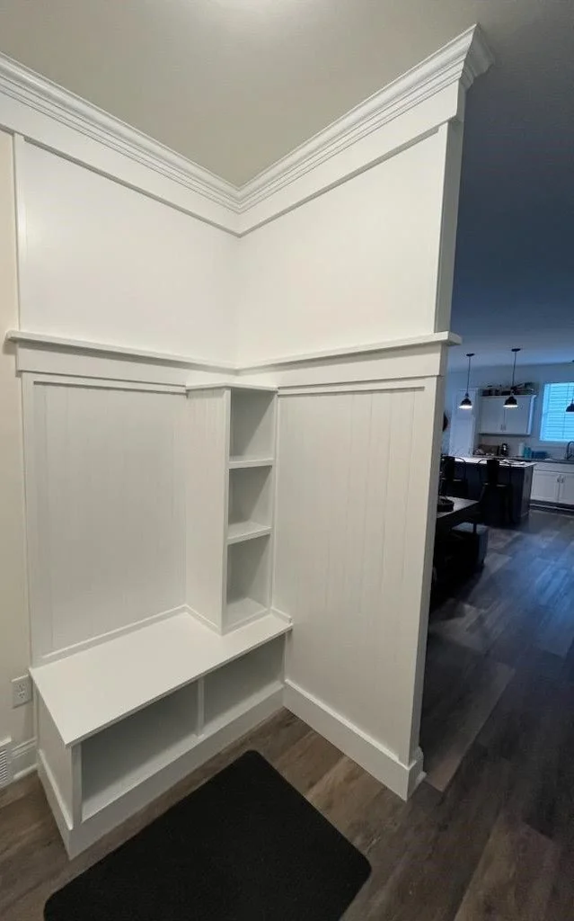 Mudroom off garage shelving bench seat, crown ceiling trim, wainscotting back wall with a wall accent top trim