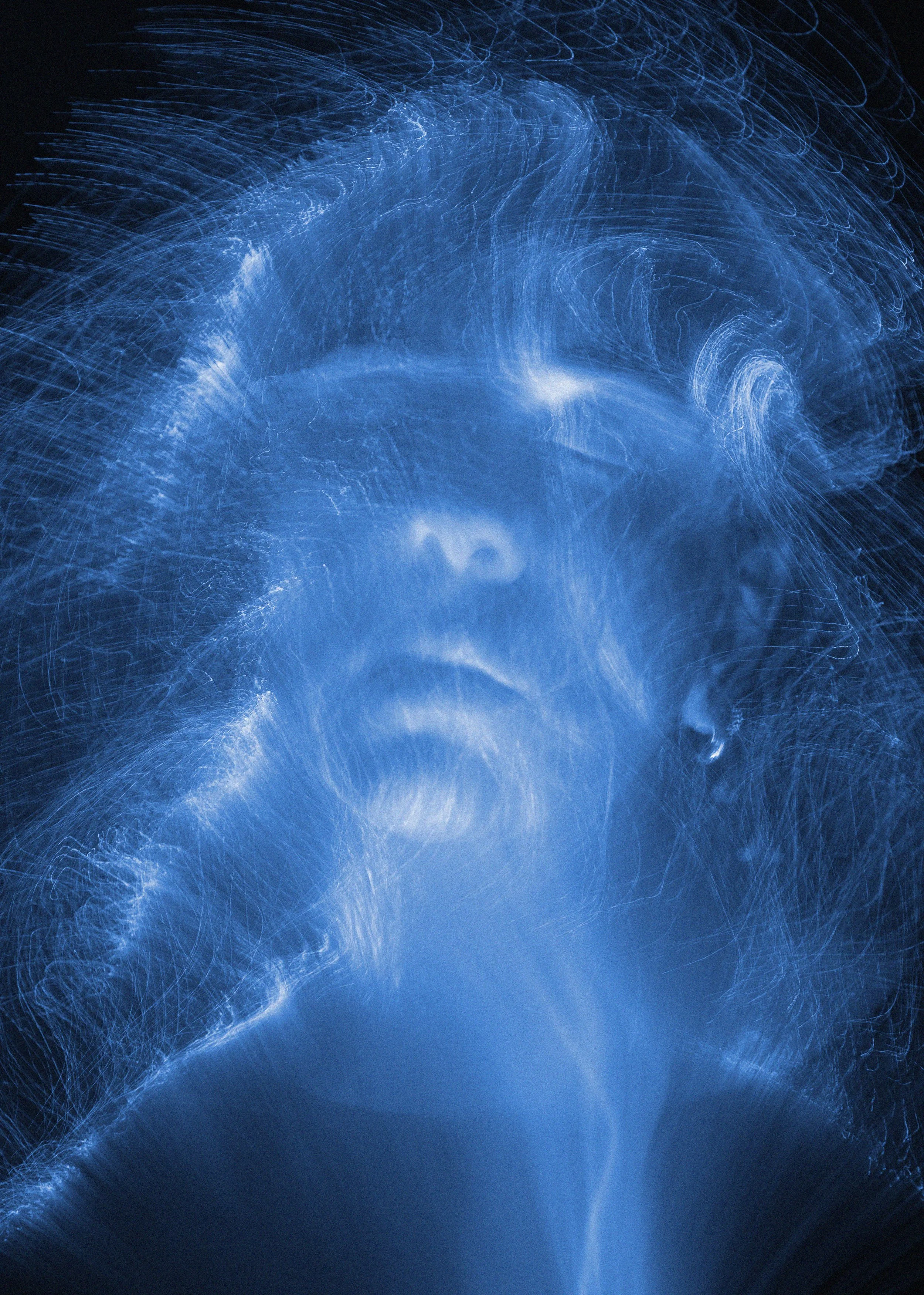 Abstract blue light trails or streaks creating a dynamic, swirling pattern against a dark background.