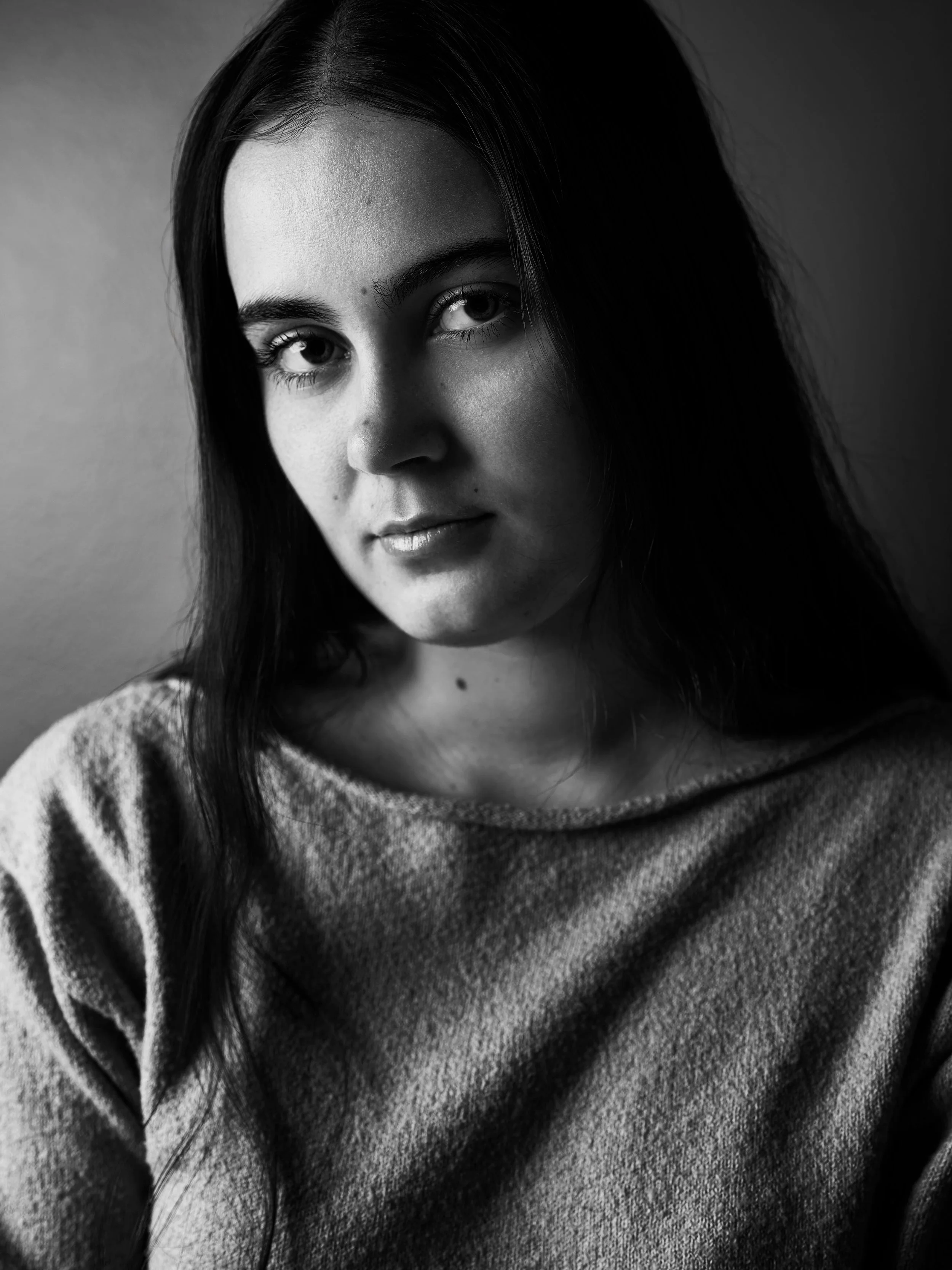 Black and white close-up portrait of a woman with dark hair, wearing a soft sweater.