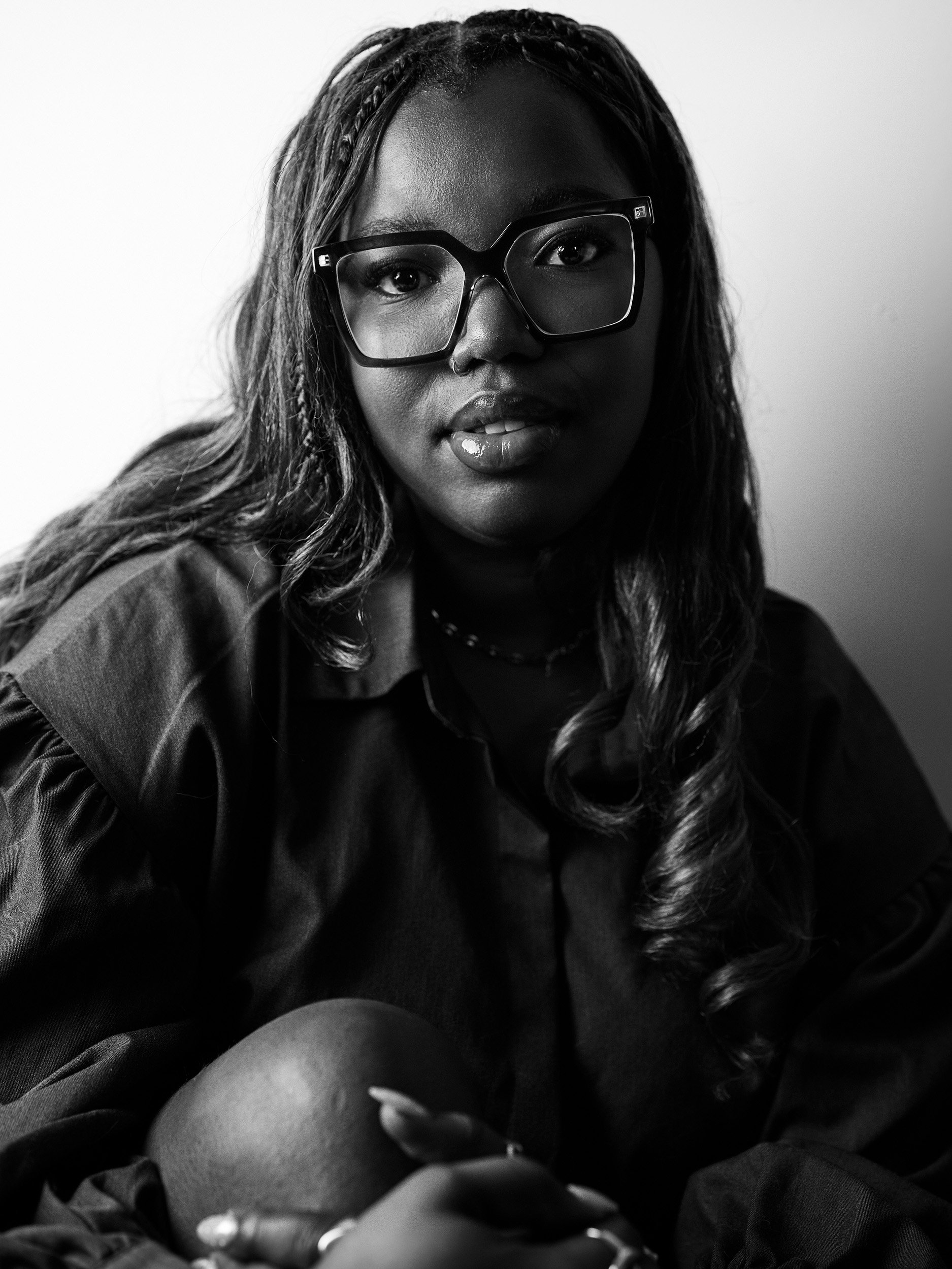 Black and white portrait of a woman with long, wavy hair wearing glasses, looking directly at the camera.