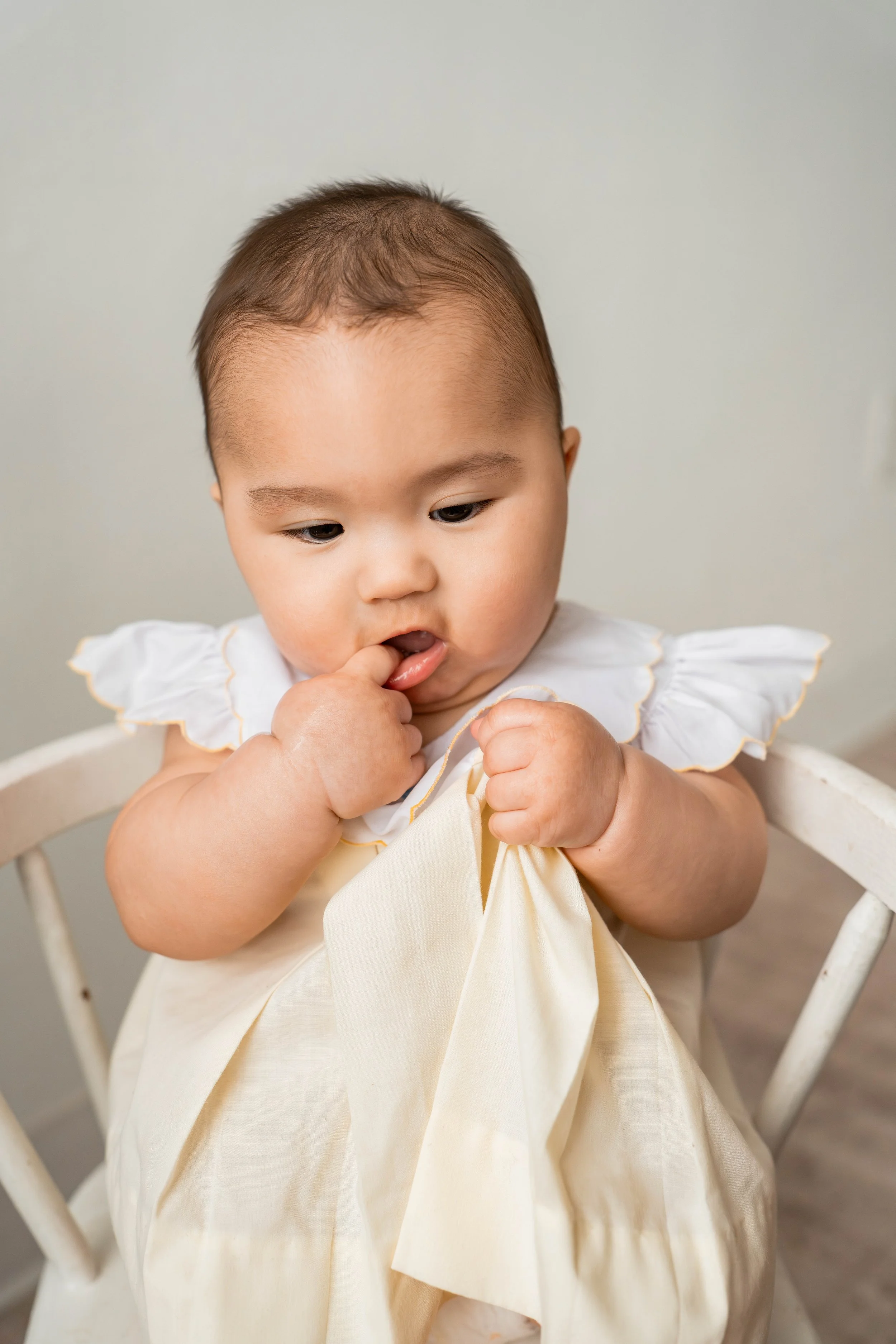 baby girl holding onto her yellow dress