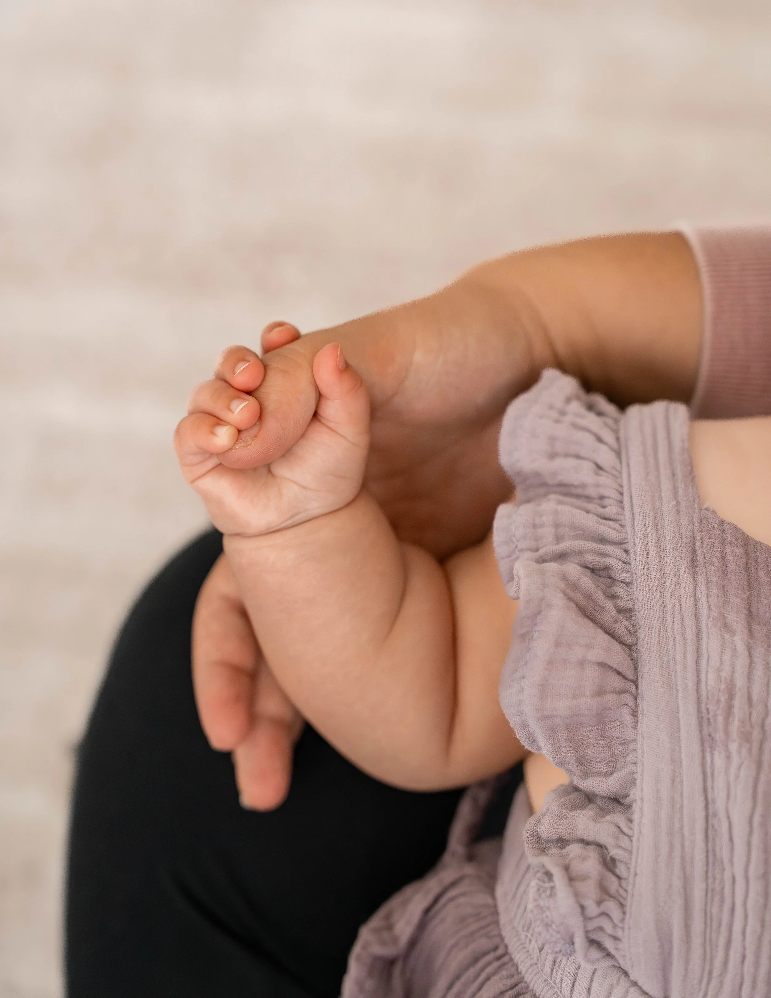 Baby girl holding tight to mommy's hand during her session