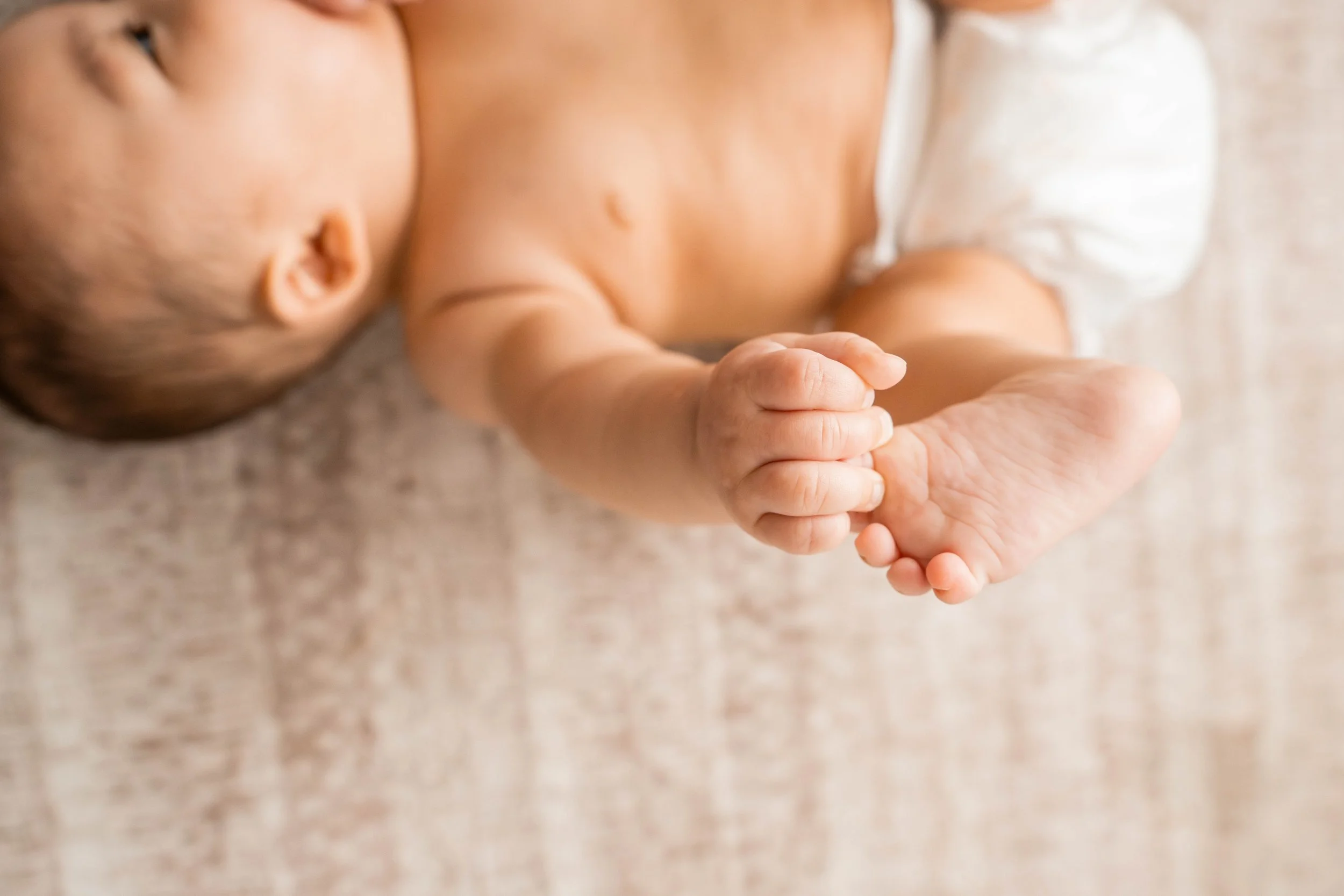 Baby girl in a diaper grabbing her toes
