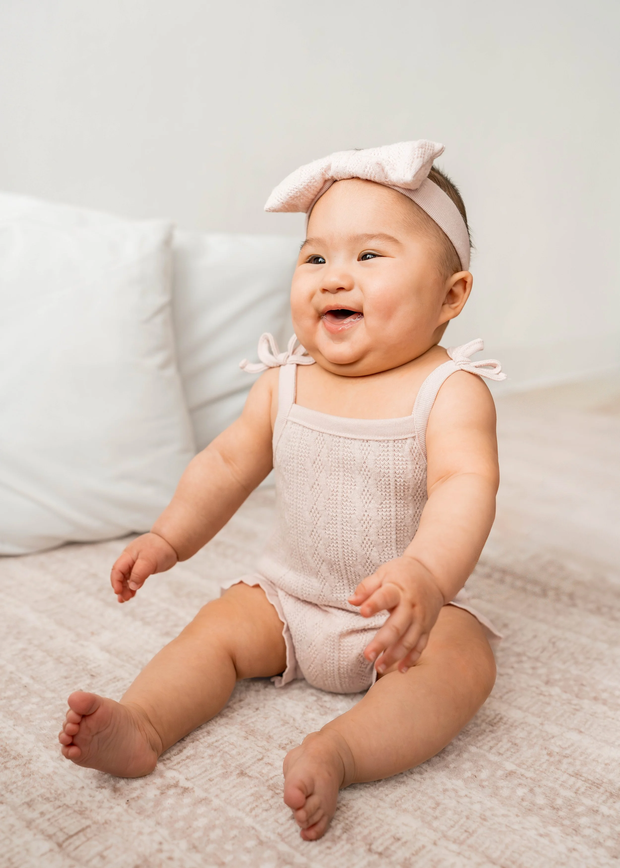 Baby girl smiling with a pink bow 