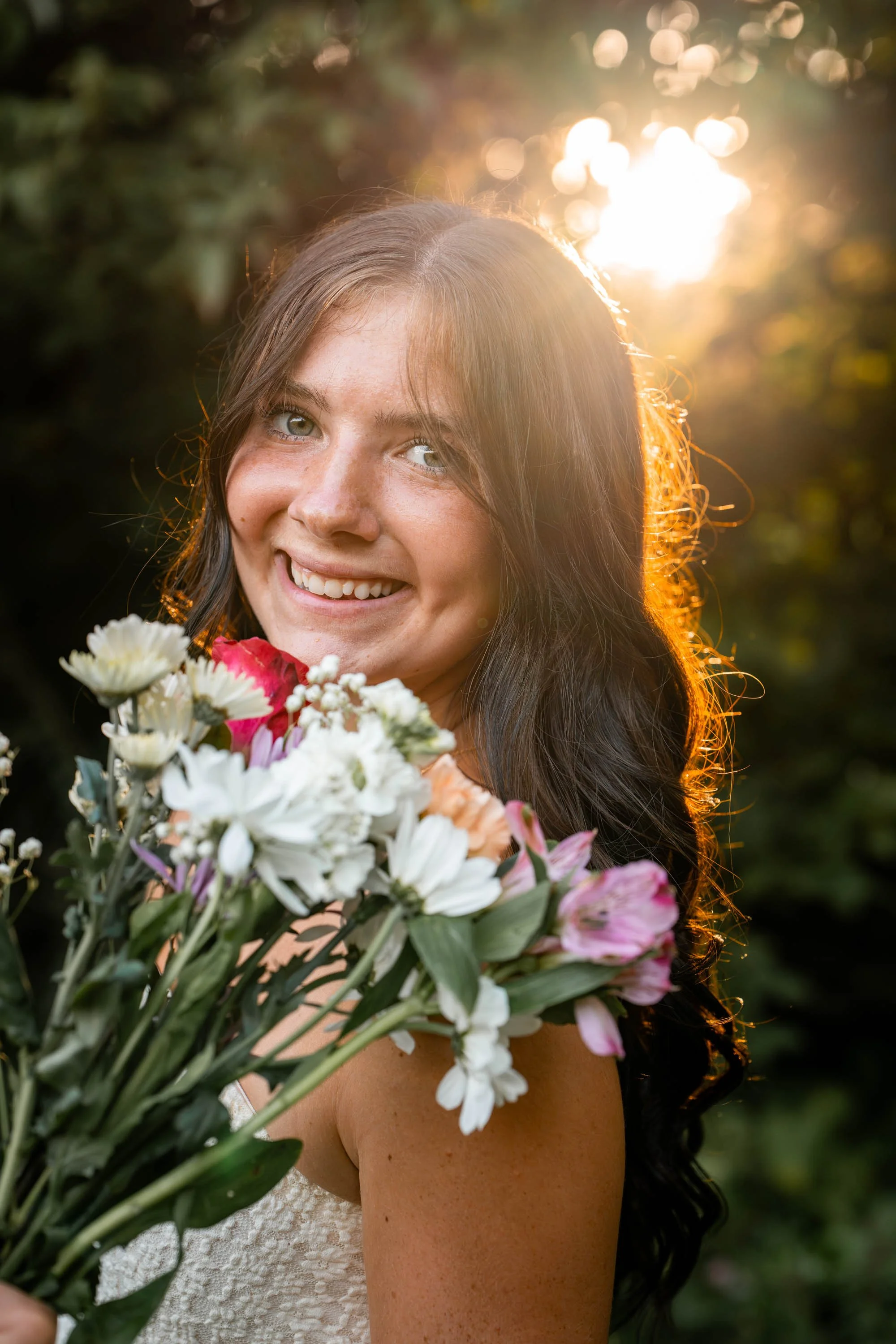 a girl smiles at the camera with a bouquet of flowers