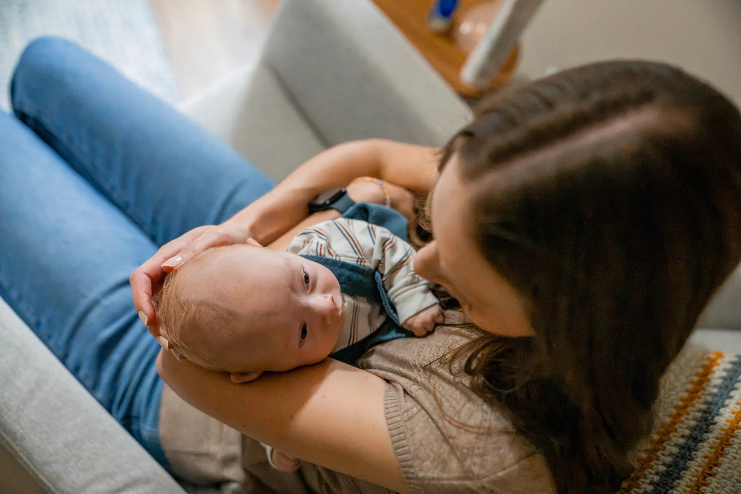 Mom looking into baby boy's eyes as she holds him in a rocking chair